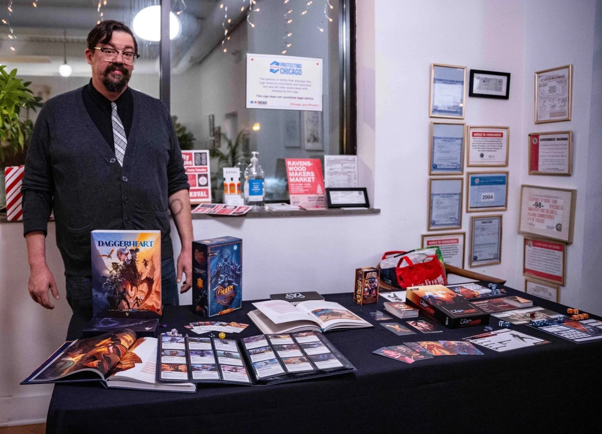 Will Hindmarch, at the Darrington Press table, displaying game sets and dice.