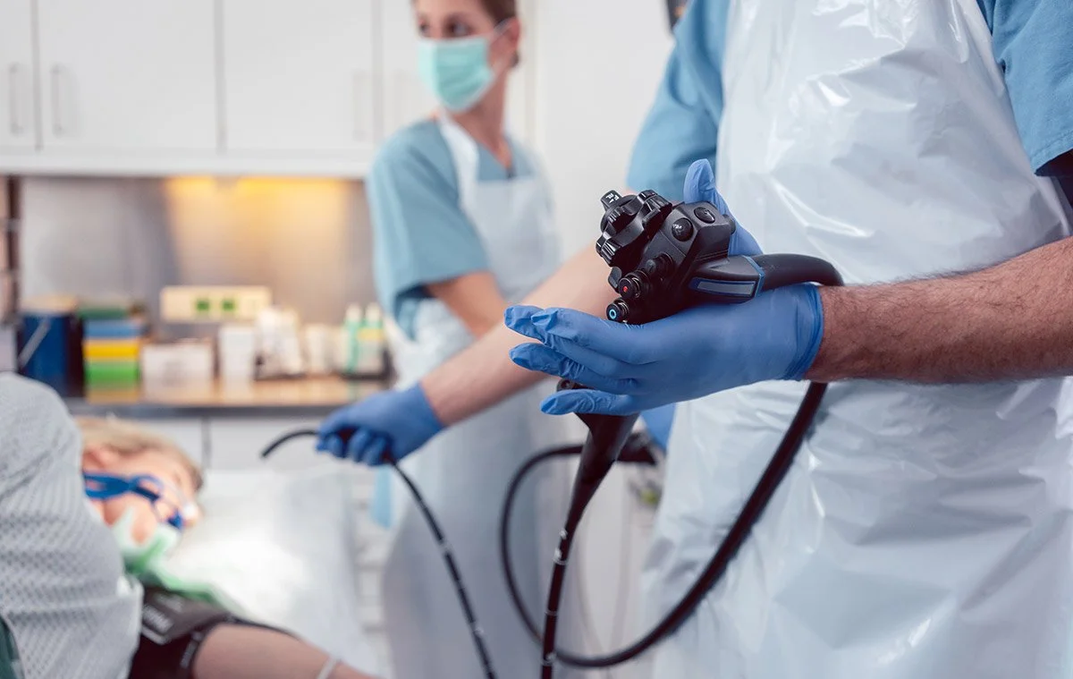 Healthcare professionals performing a medical procedure in a hospital room, with one holding a medical instrument.