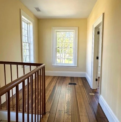 Empty hallway with wooden floor and windows