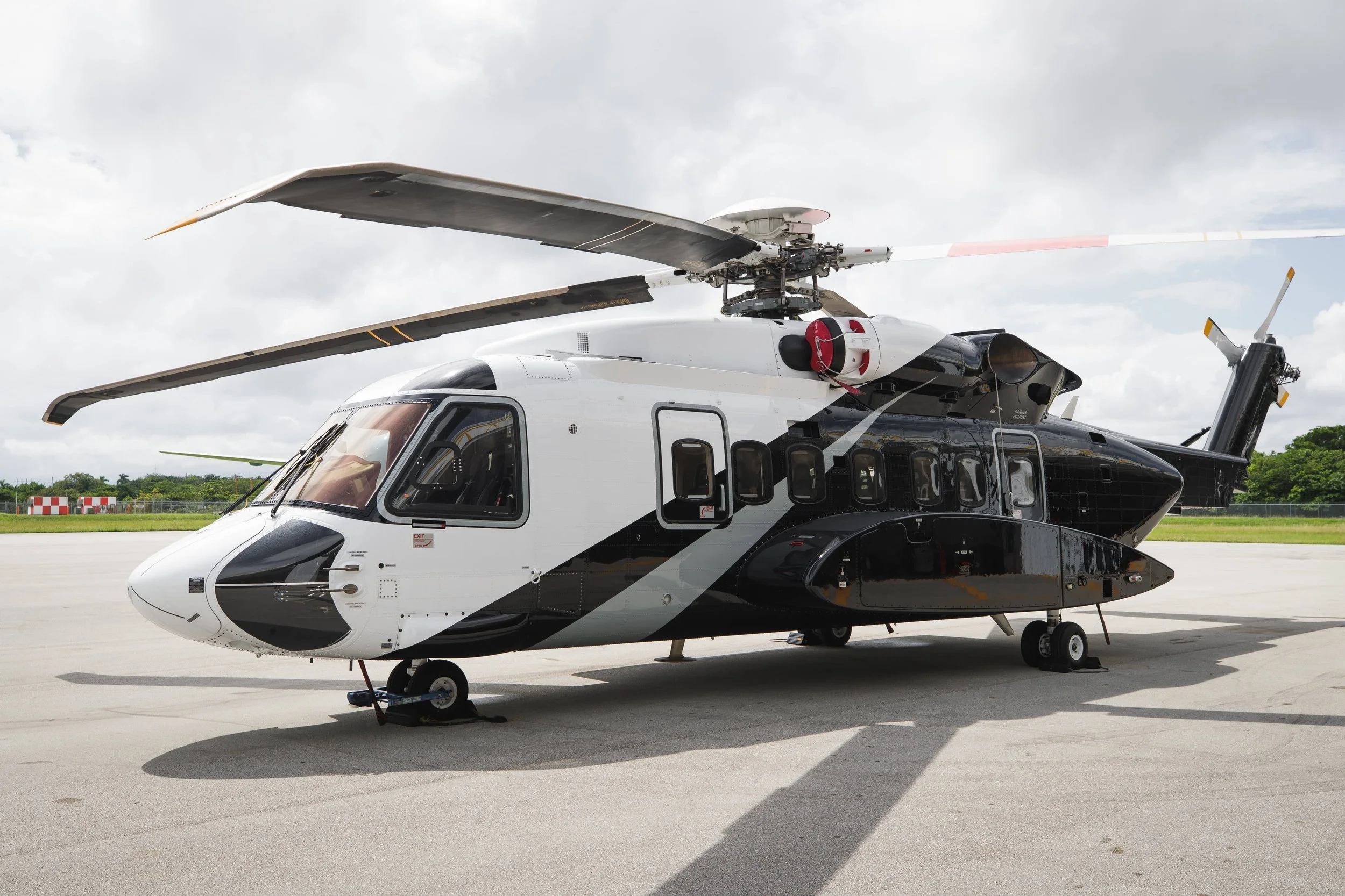 A military helicopter on a tarmac with a cloudy sky in the background.