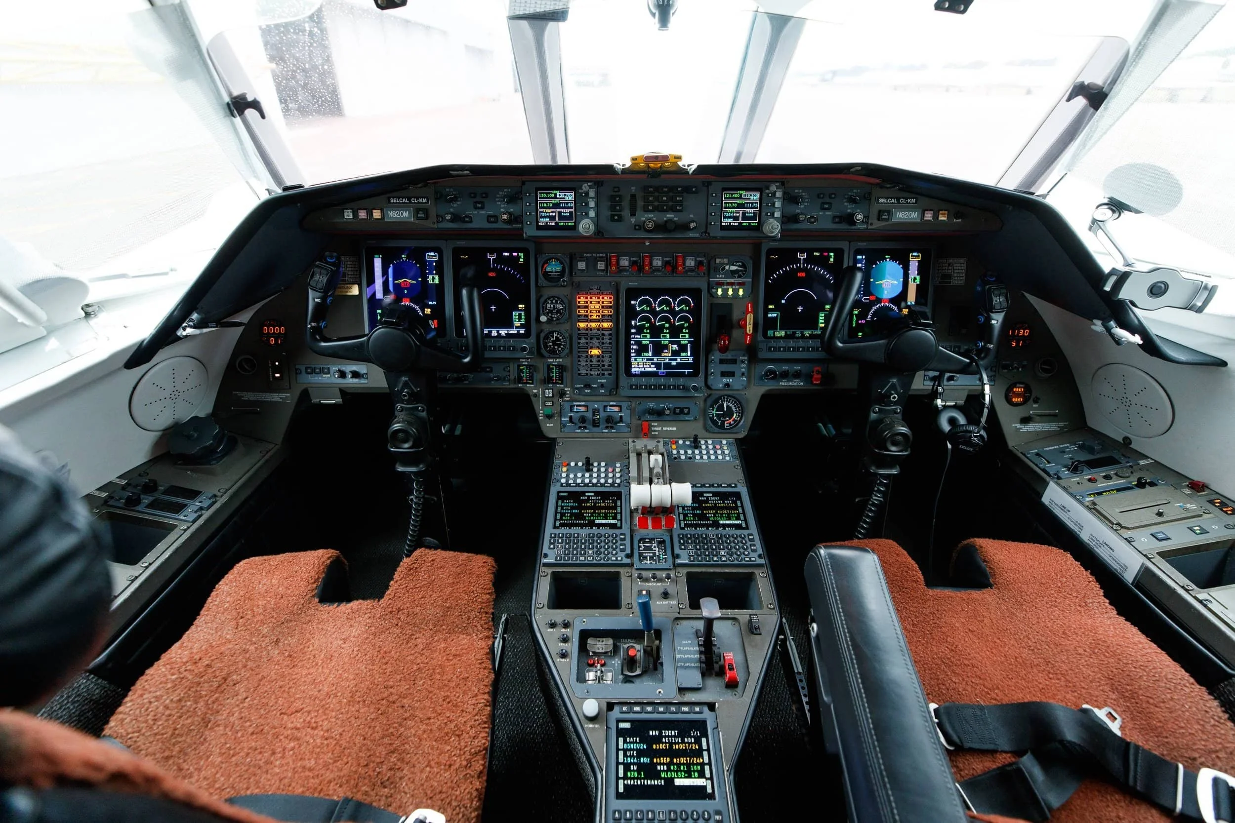 Cockpit of a commercial airplane with various digital displays, control panels, and steering yokes.