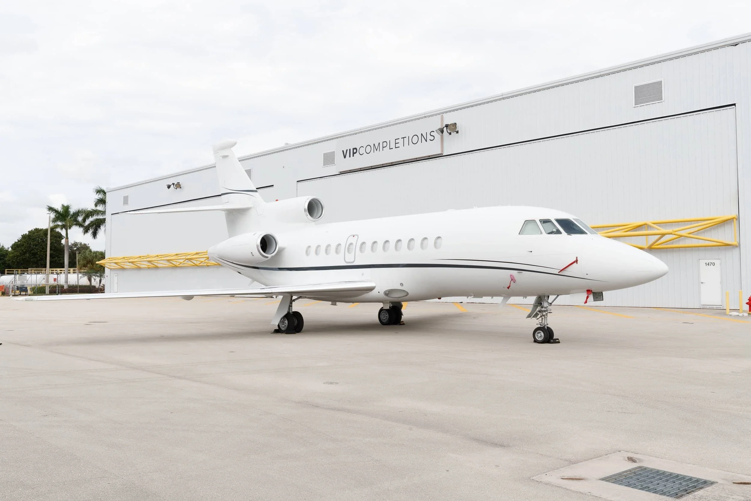 A white private jet parked outside a building labeled 'VIP COMPLETIONS' on an airport tarmac.