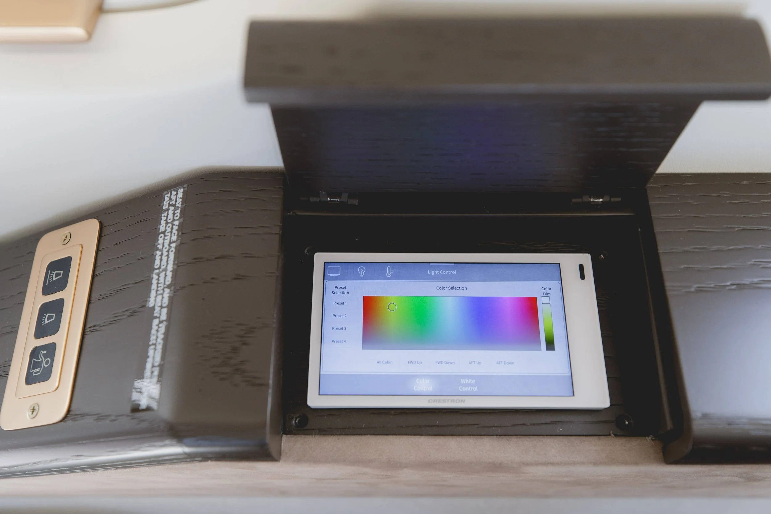 A touchscreen control panel inside a black cabinet, displaying color adjustment options for a lighting system with a color spectrum bar.