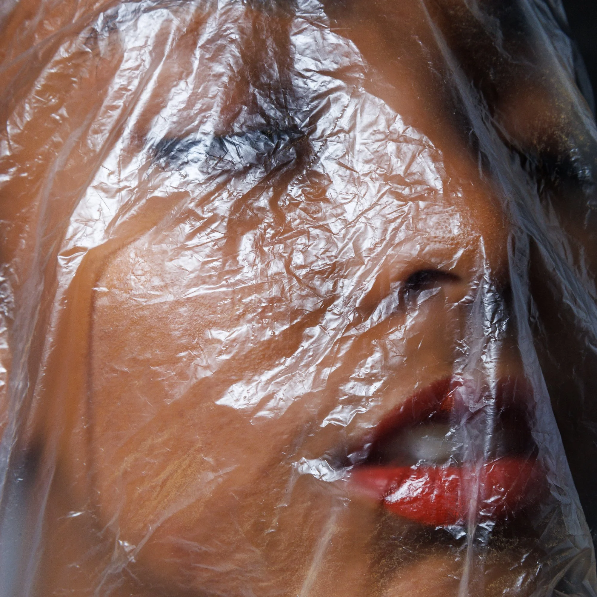 Maquillage d'une femme avec un visage partiellement couvert de plastique transparent