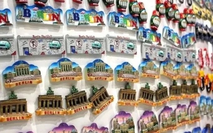 A display rack filled with souvenir magnets featuring images of Berlin landmarks and attractions.