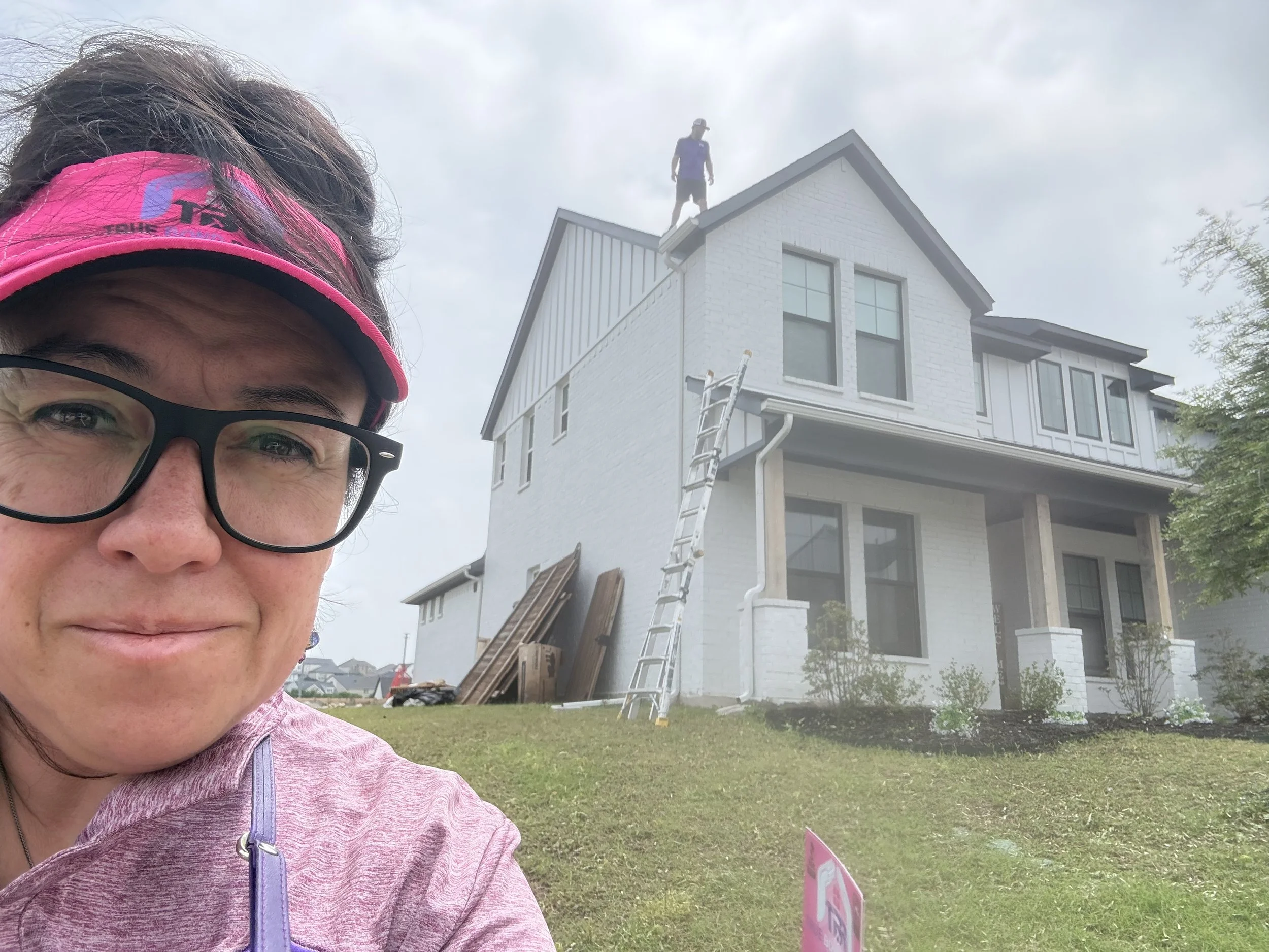 Tiffany of True Bond Roofing at a residential roofing project in Dallas-Fort Worth, with co-owner Aaron working on the roof in the background.