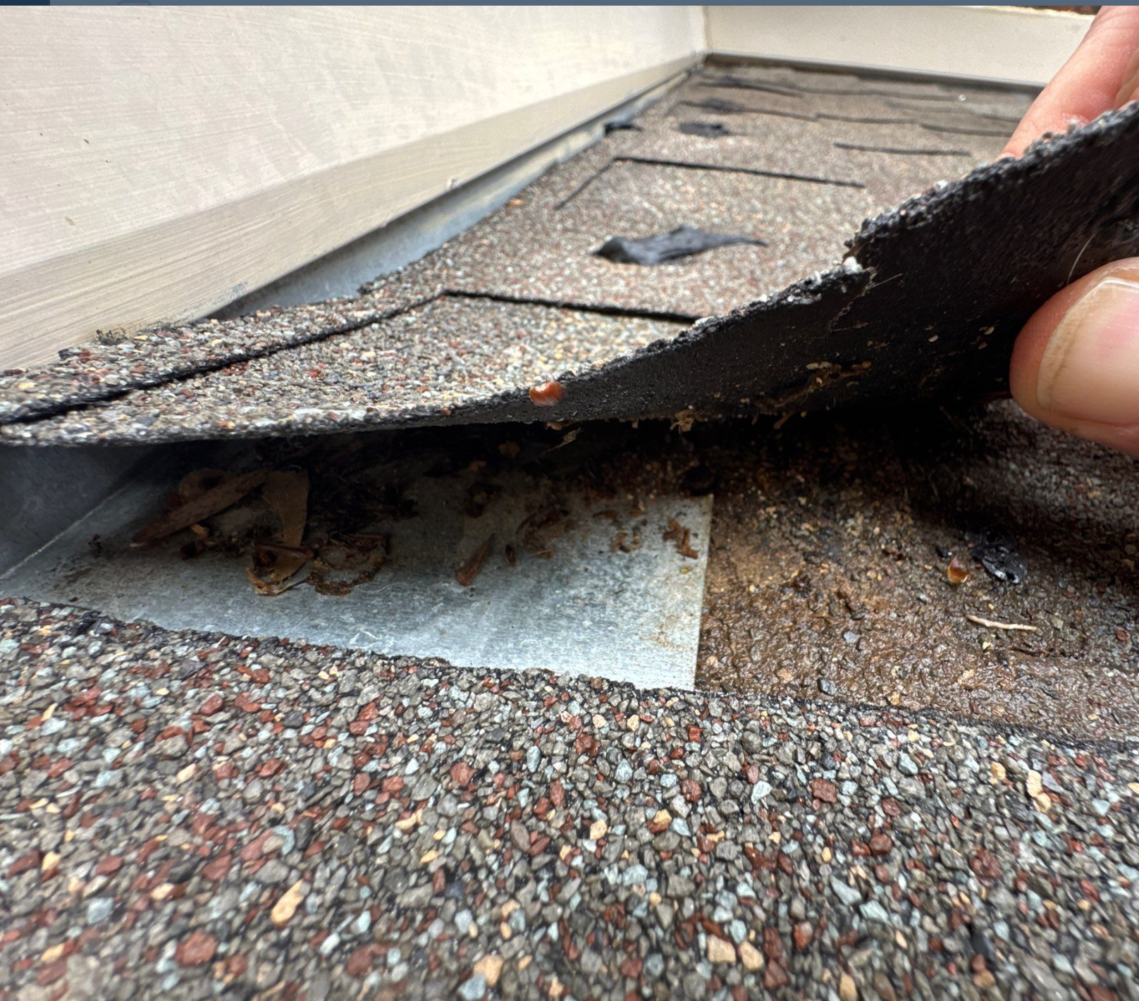 True Bond Roofing inspection revealing an improperly completed roof repair, with a lifted asphalt shingle exposing underlying roofing materials.