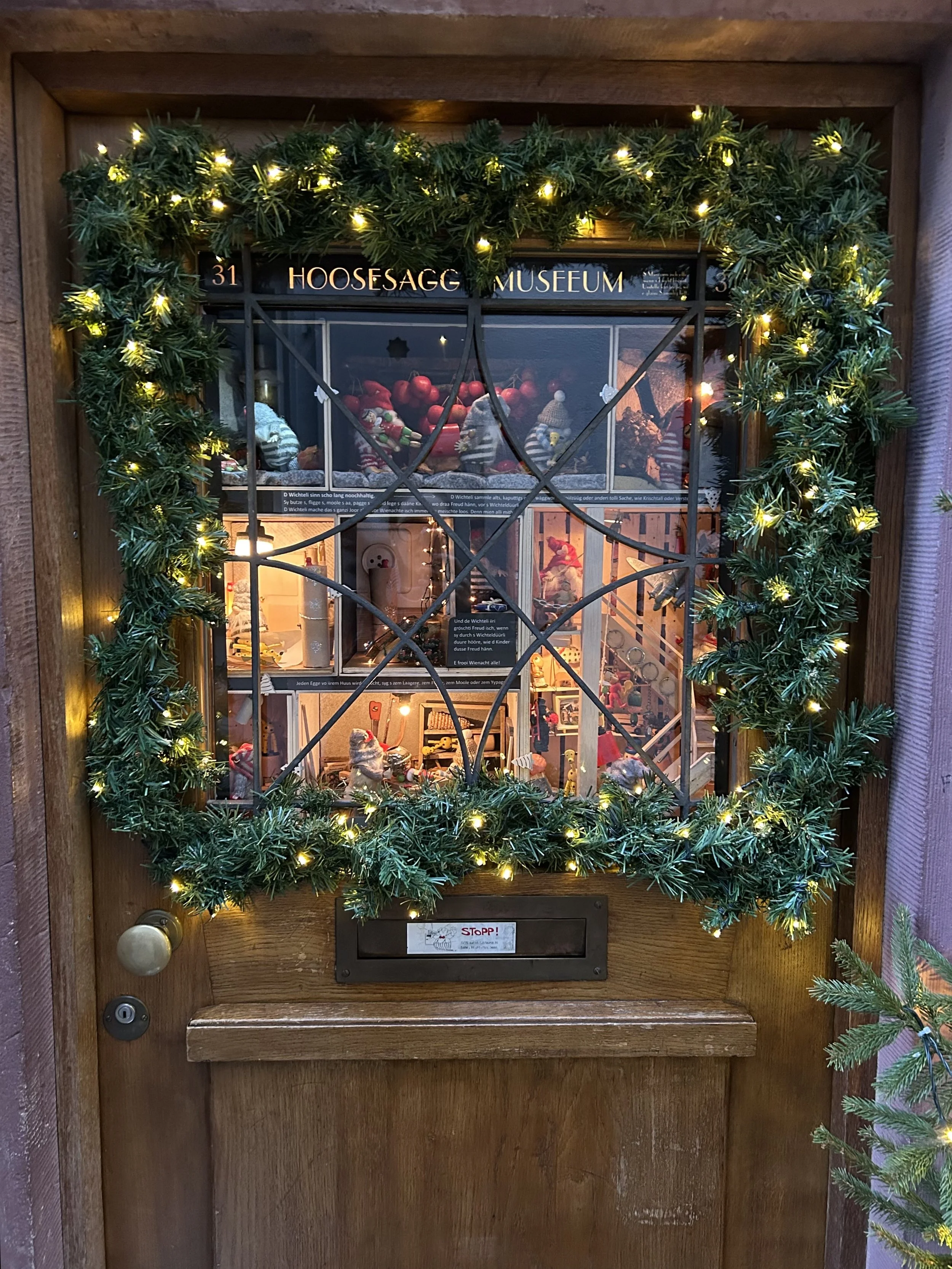The miniature Hoosesagg Museum in Basel, decorated with Christmas garland and warm lights around the small window.