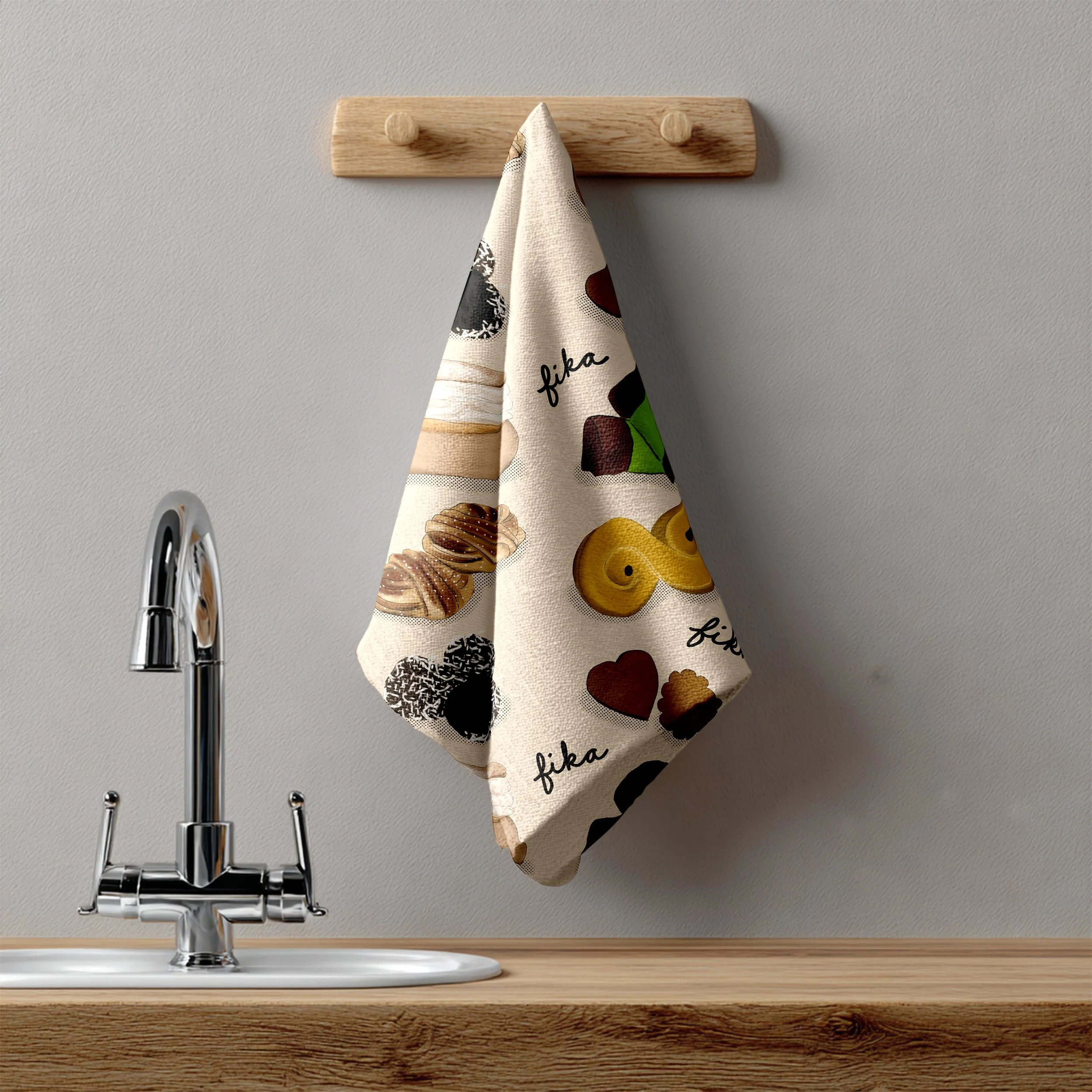 A mock up of a linen tea towel printed with an illustrated Swedish fika pastry pattern featuring kanelbullar, chokladbollar, dammsugare, and more in warm tones on a cream background - hanging from a wooden peg rail above a kitchen sink.