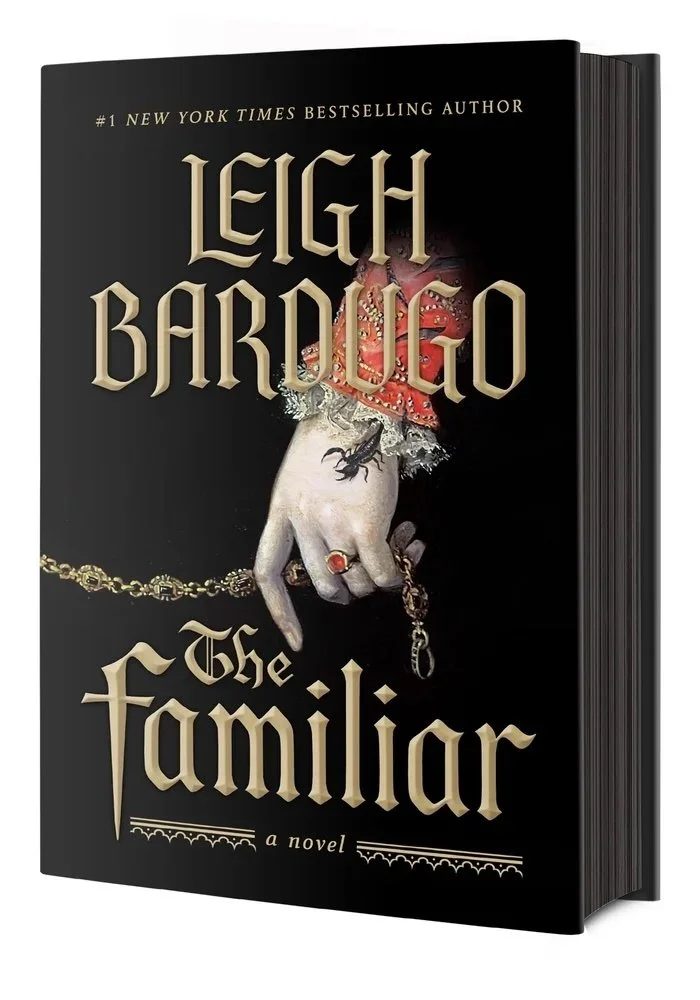Cover of The Familiar by Leigh Bardugo, featuring a dramatic hand holding a chain on a black background with gothic gold typography.