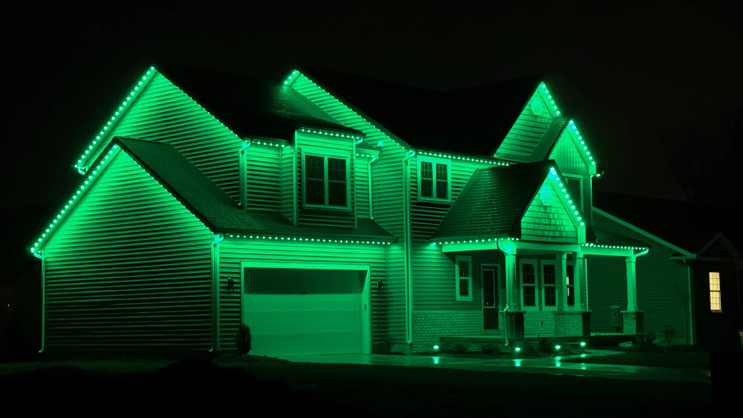 House decorated with green holiday lights at night.