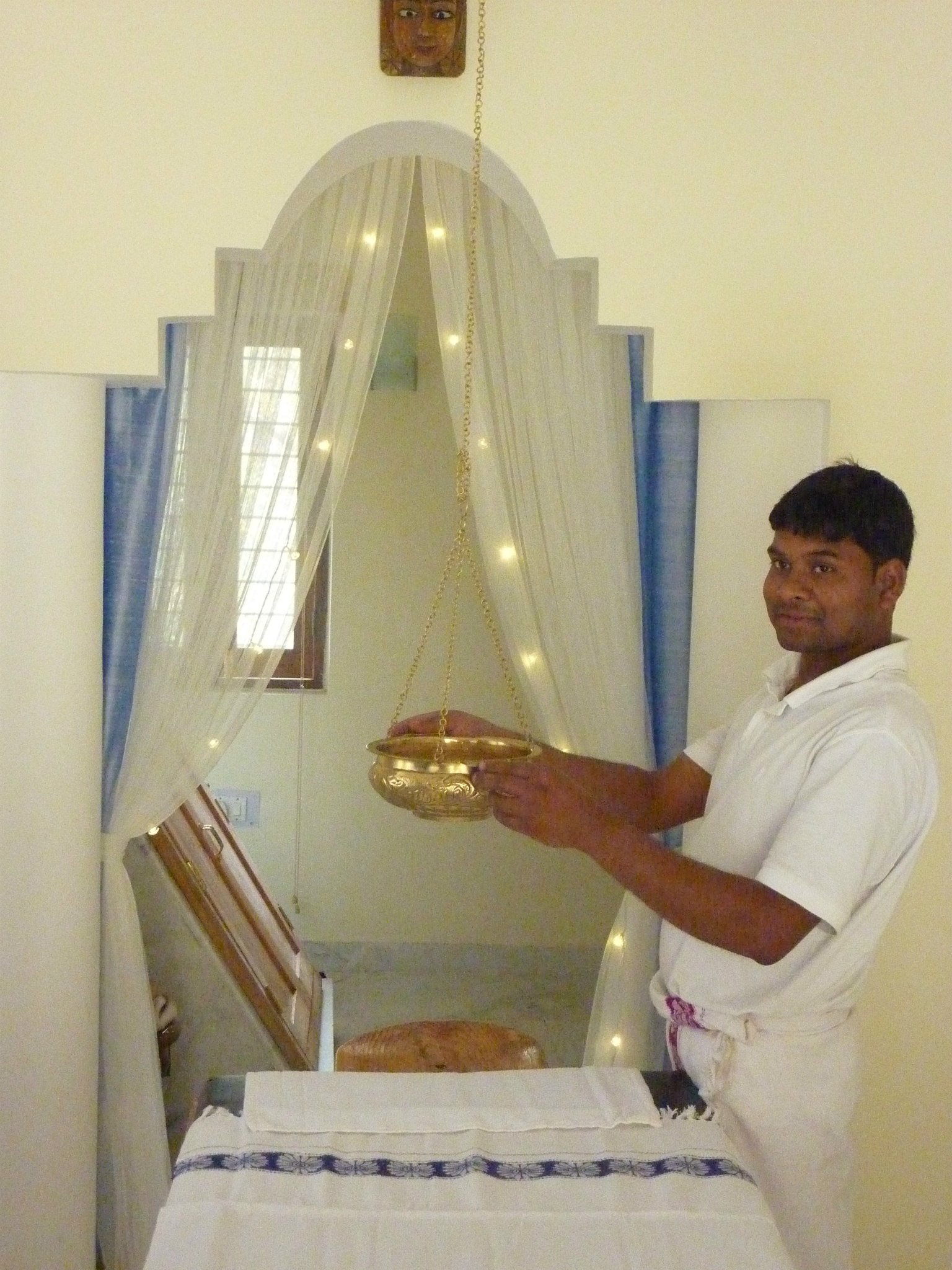 Ayurvedic practitioner holding Shirodhara copper vessel at wellness center in India, symbolizing intentional healing and immersive wellness journeys