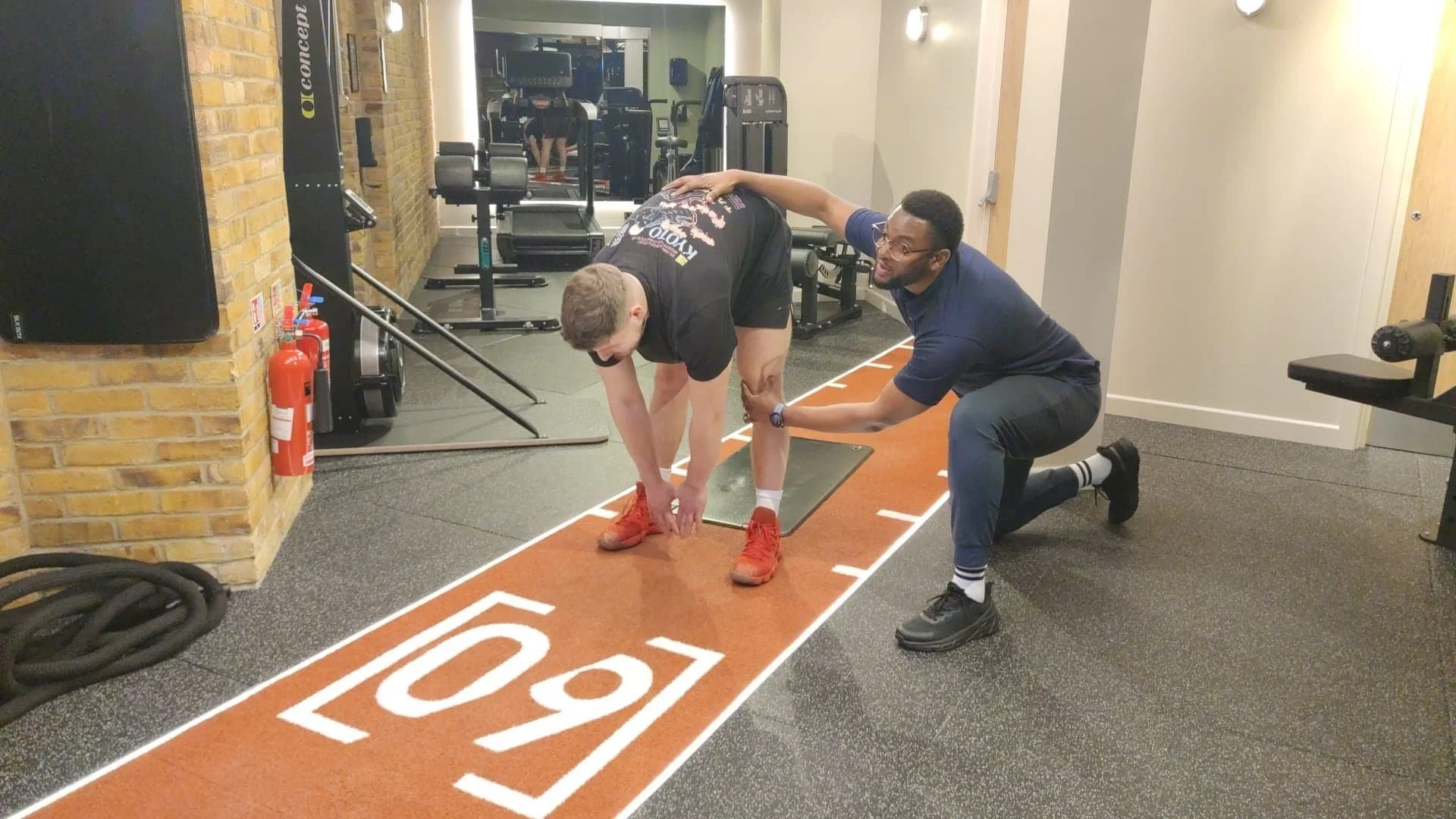 Rehab therapist aiding client with stretching in a gym setting
