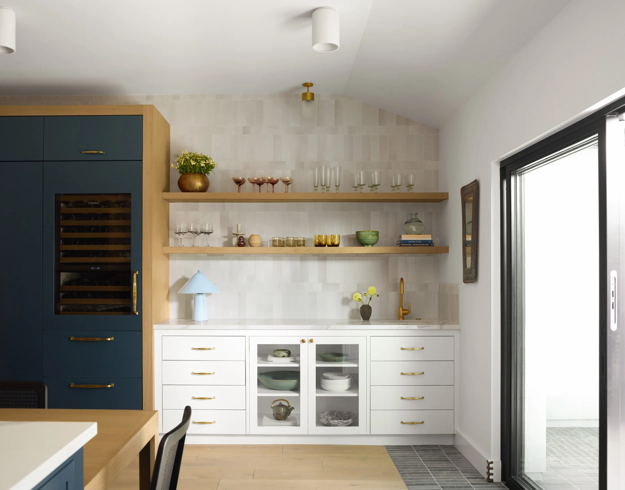 Bar area with navy cabinetry, built-in wine fridge, floating oak shelves and white glass-front cabinets