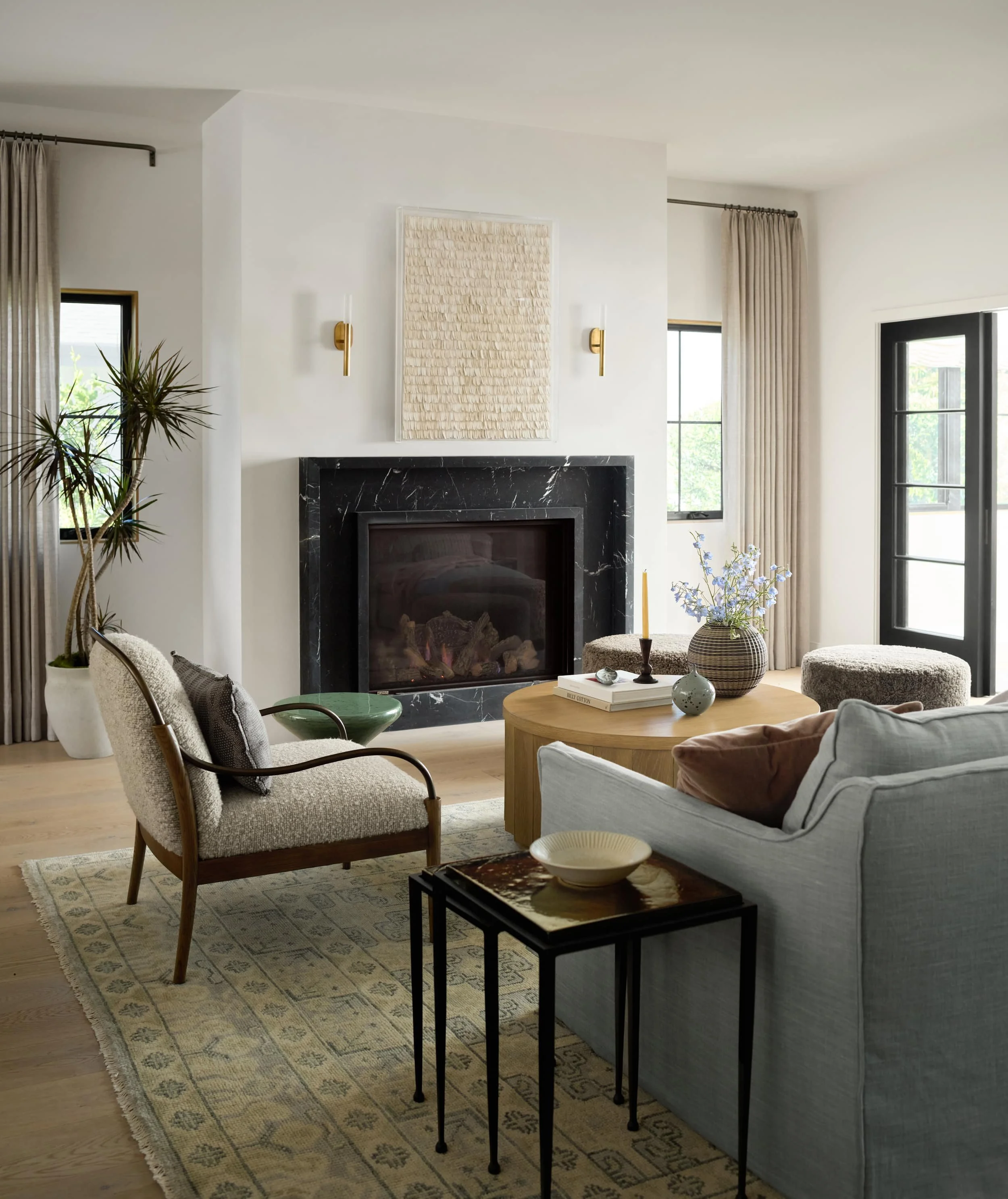 Living room with a black marble fireplace, textured art, boucle armchair and soft blue sofa