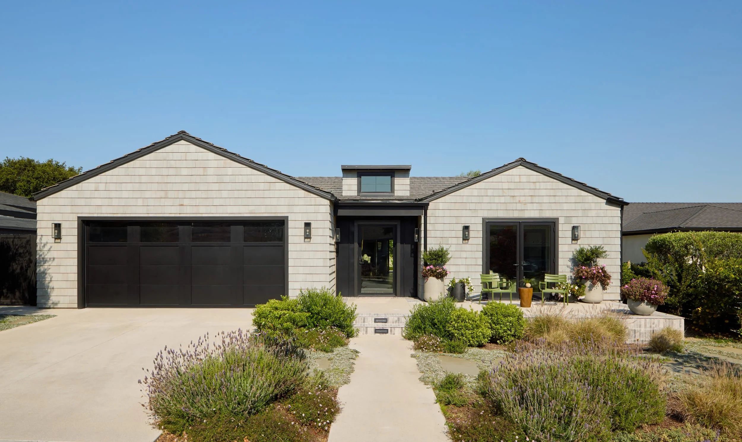 Front of a modern shingle home in Redondo Beach with a black garage door and native landscaping