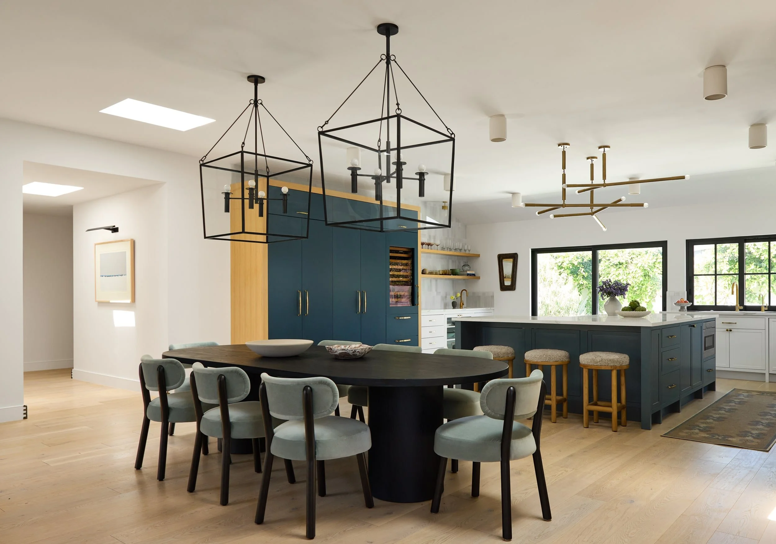 Open kitchen and dining room with black lantern pendants, oval pedestal table and sage upholstered chairs in a Redondo Beach home