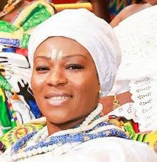 Close-up of a woman wearing traditional African attire and a white headwrap, smiling at a celebration or cultural event.