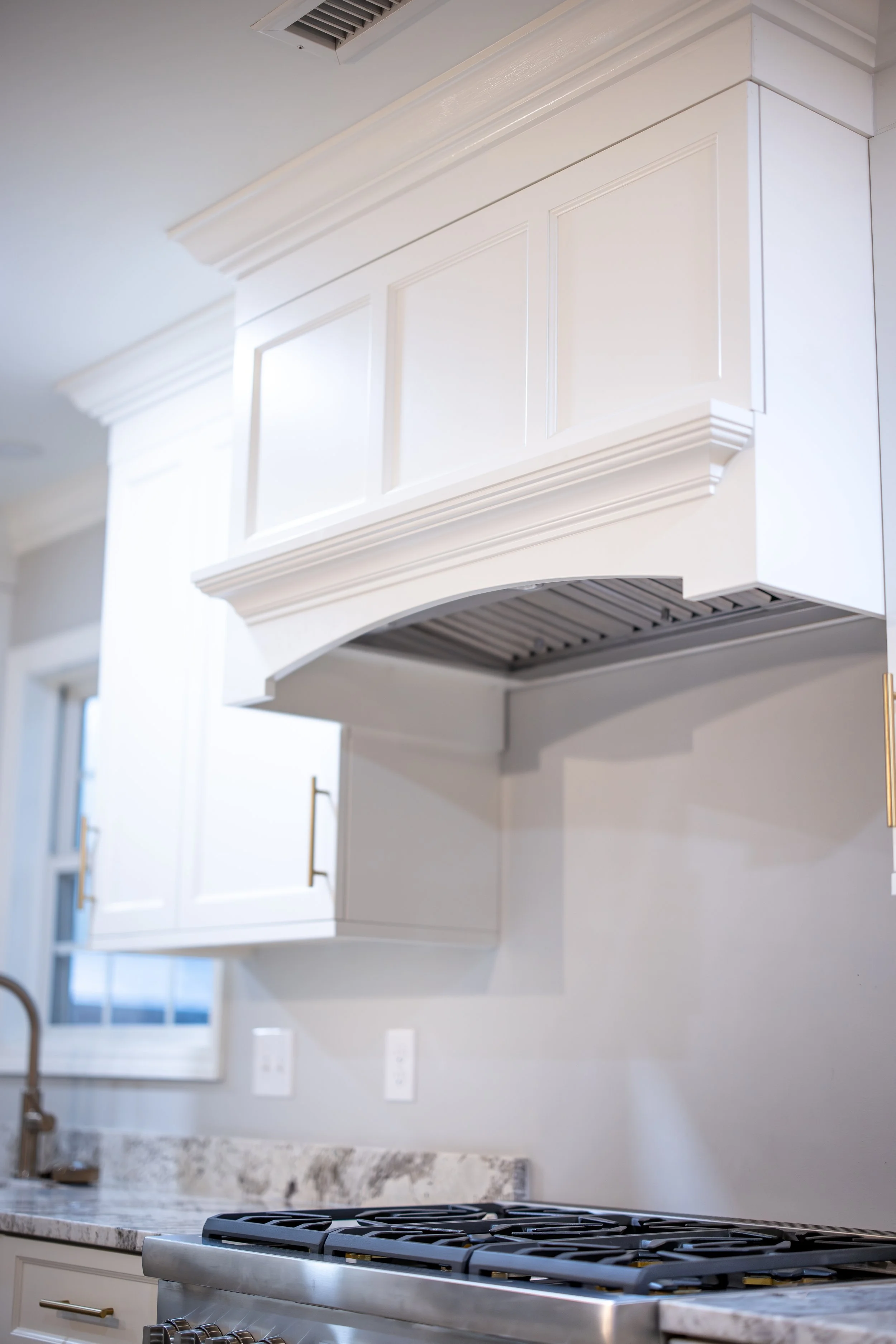 Close-up of a modern kitchen with white cabinets, patterned marble countertop, and a stainless steel stove.