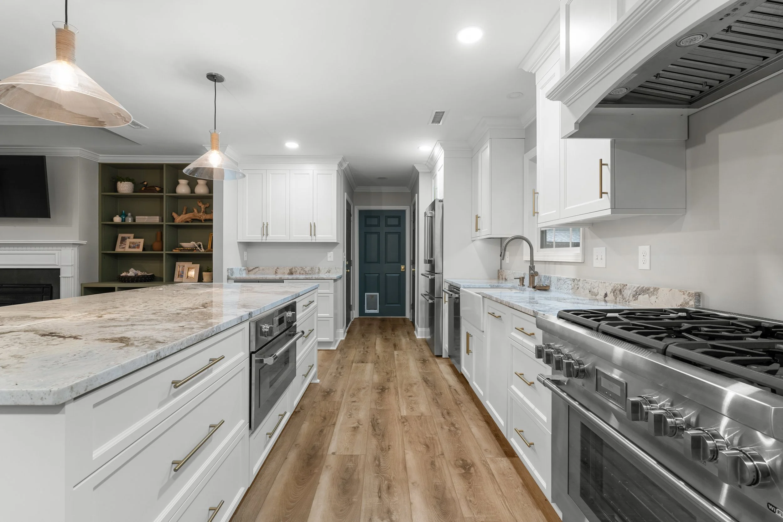 Modern kitchen with white cabinets, stainless steel appliances, granite countertops, and hardwood floors.