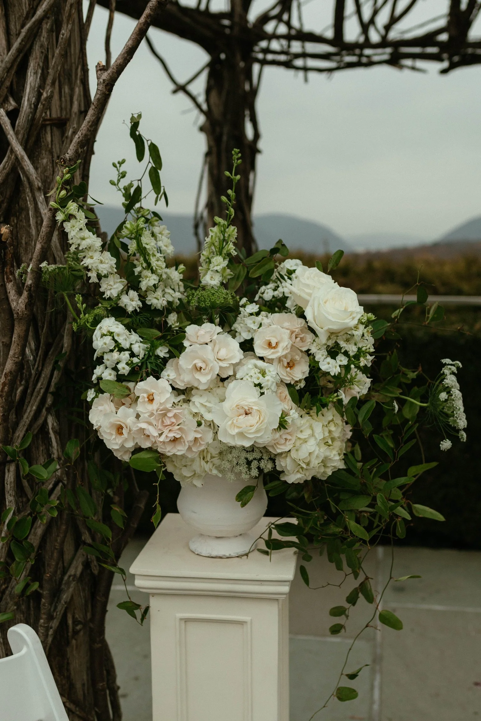White floral arrangement with roses, hydrangea, phlox, and queen annes lace on a pedestal stand at The Garrison in the Hudson Valley