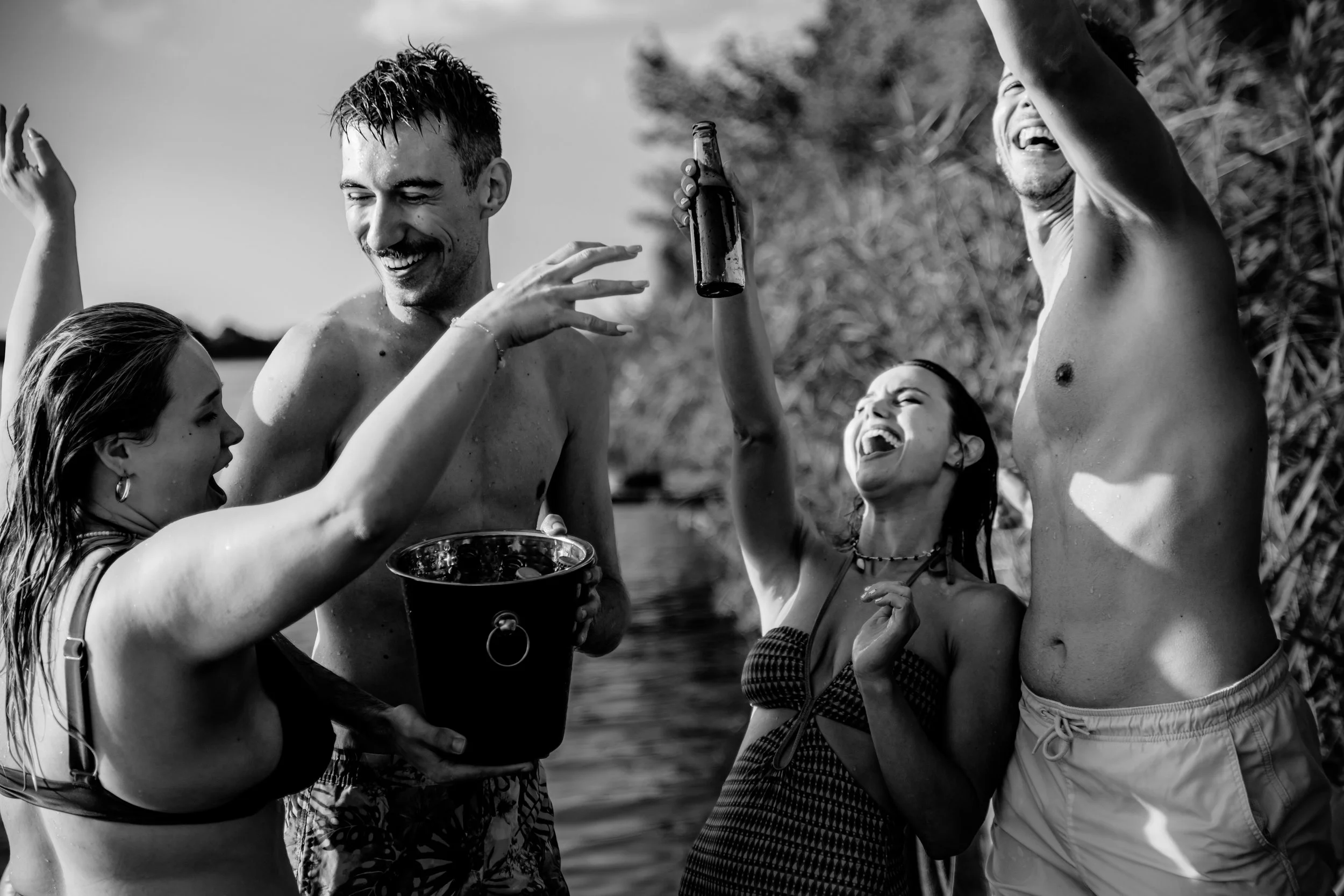 Grupo de amigos disfrutando en la playa, celebrando con cerveza y risas, en un ambiente relajado y feliz.