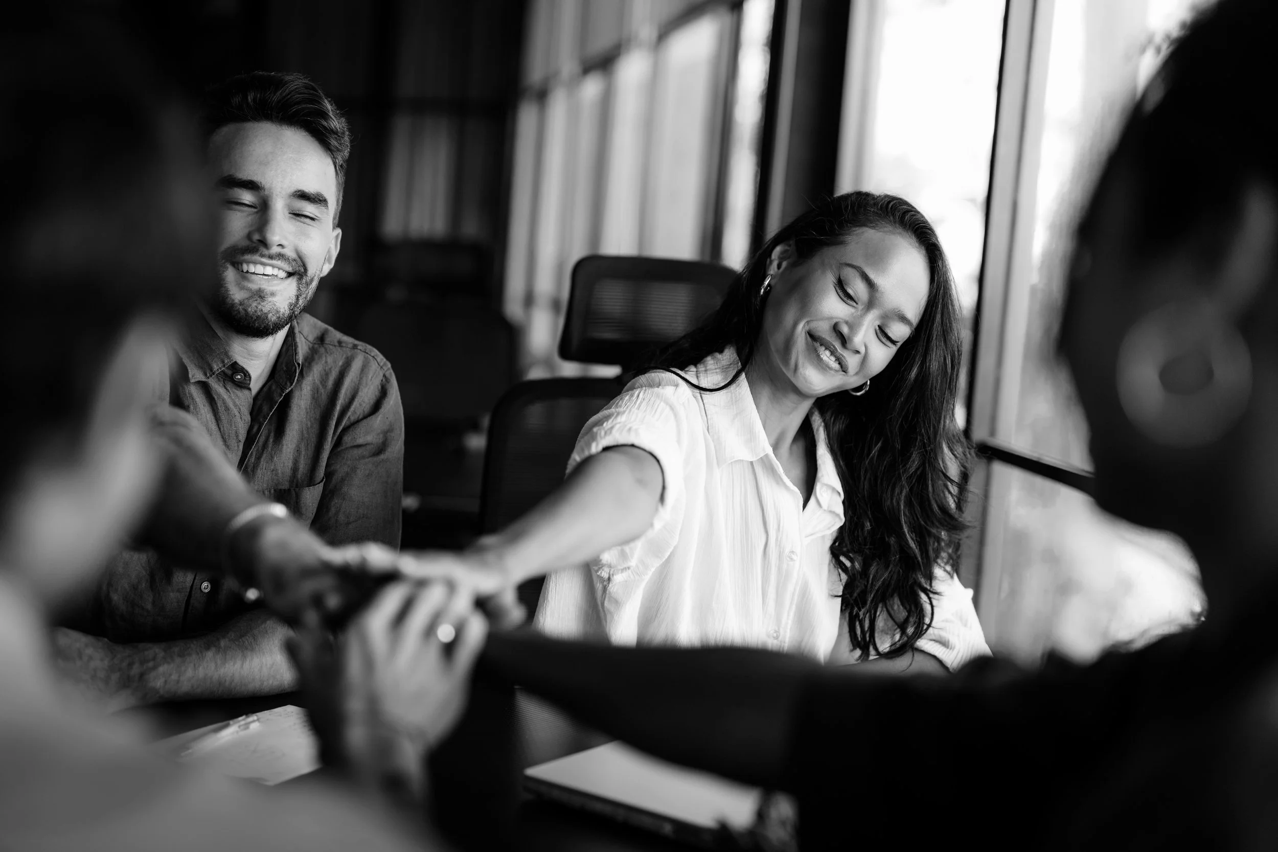 Grupo de personas sonriendo y compartiendo momentos en una reunión de trabajo en una oficina