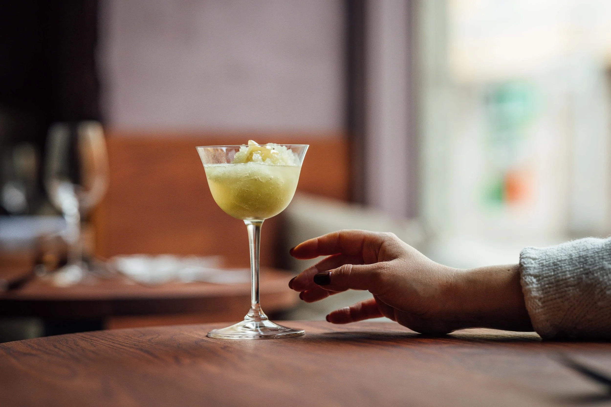 Cocktail being served at Flor Helsinki, organic drink in a wine bar setting with hand pouring glass