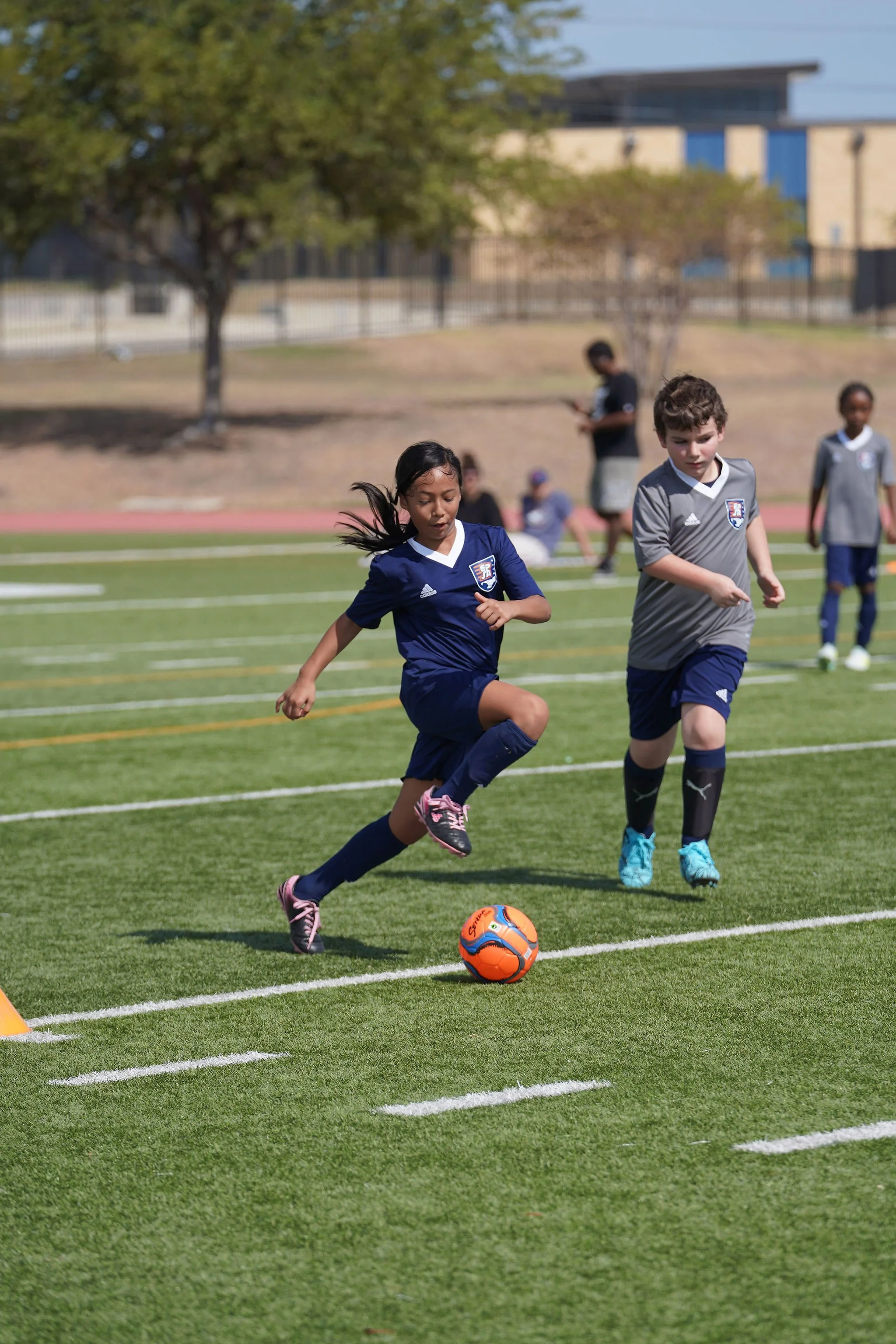 Youth soccer training session with children and coaches on a grassy field.