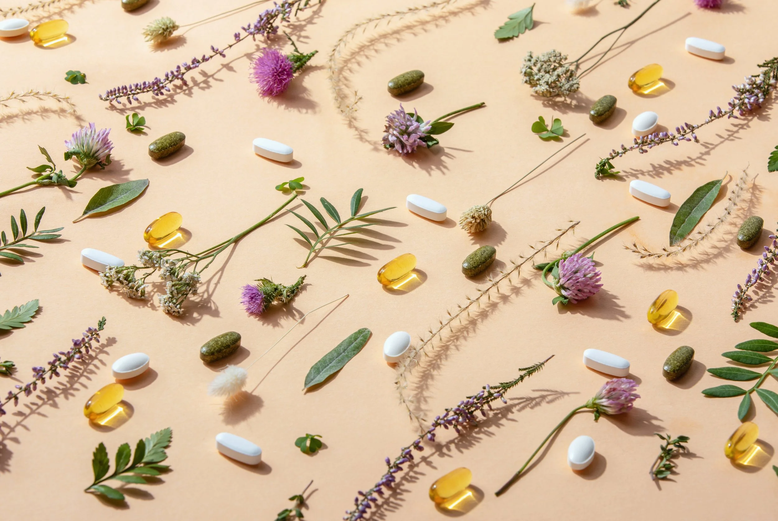 Various herbs, flowers, leaves, and pills arranged on a beige background.