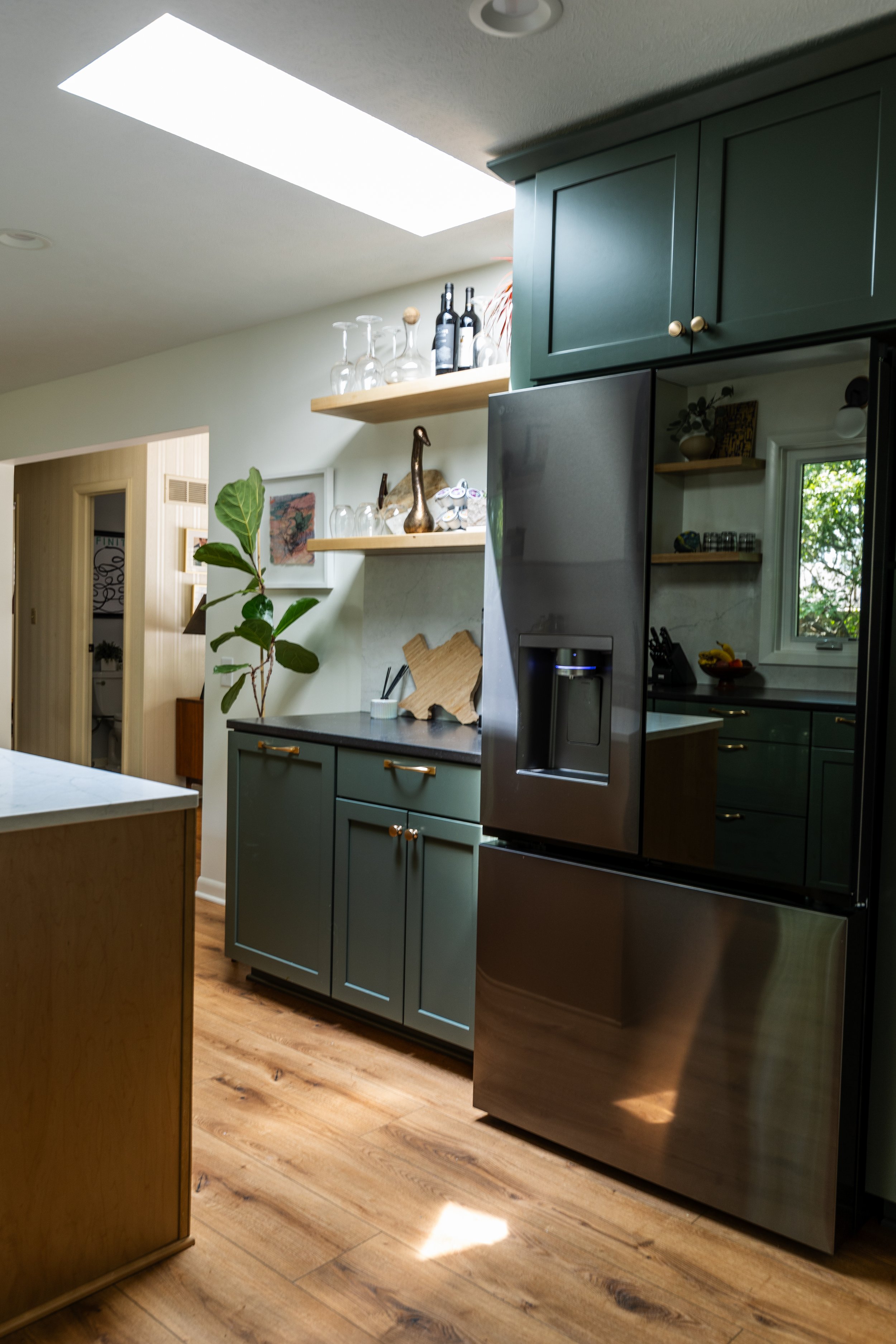 1962 Kitchen Remodel, dark green cabinets, white quartz island, wooden floors, brass hardware, wood cabinets, custom hood, floating shelves, dark countertops, open shelving
