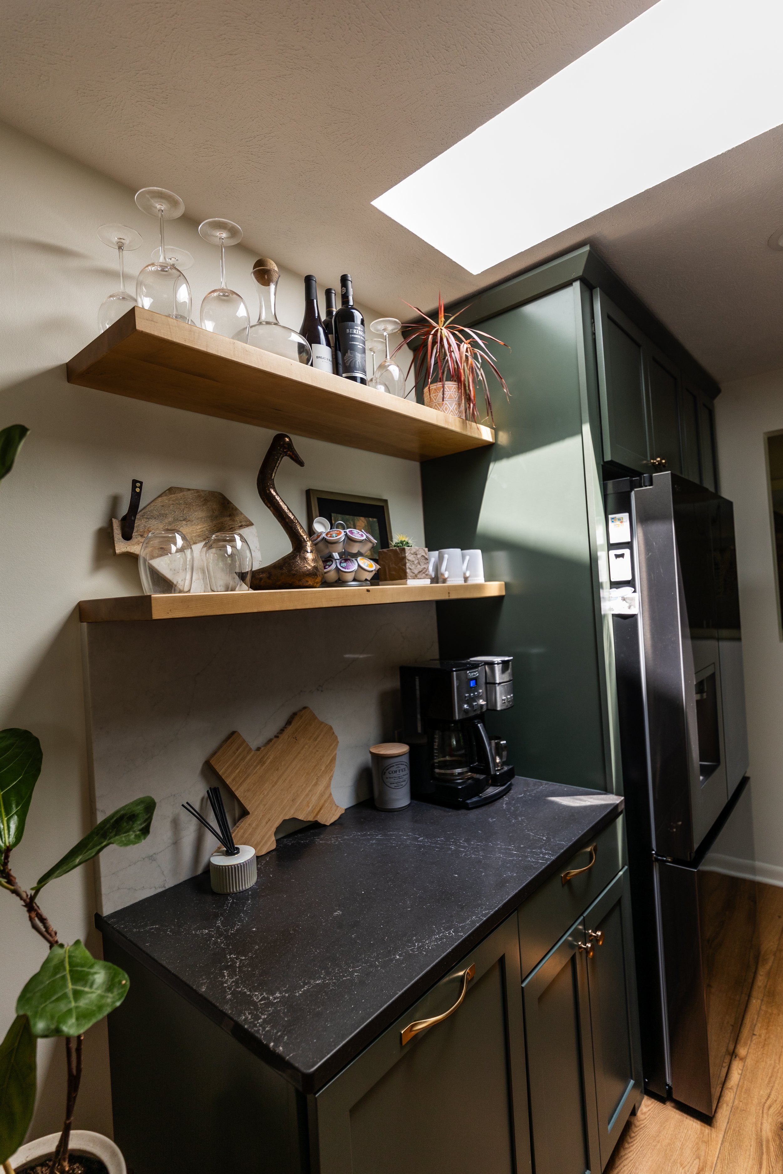 1962 Kitchen Remodel, dark green cabinets, white quartz island, wooden floors, brass hardware, wood cabinets, custom hood, floating shelves, dark countertops, open shelving, large windows.
