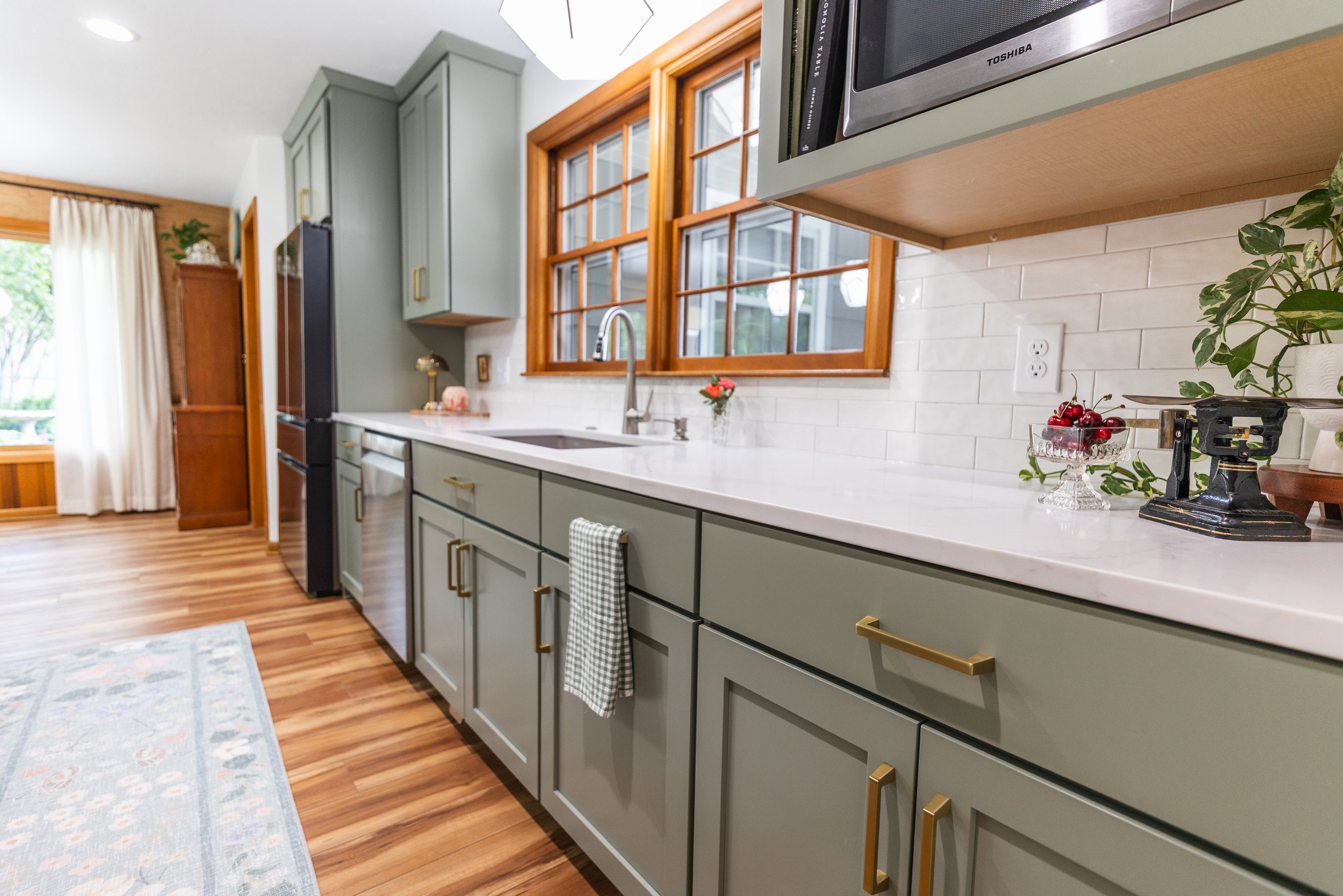 1958 Kitchen Remodel, mid century design, wood floors, stainless steel appliances, sage green cabinets, brushed gold hardware, white quartz countertop, modern light fixtures, Lincoln Nebraska, professional contractors, remodeling and renovations.