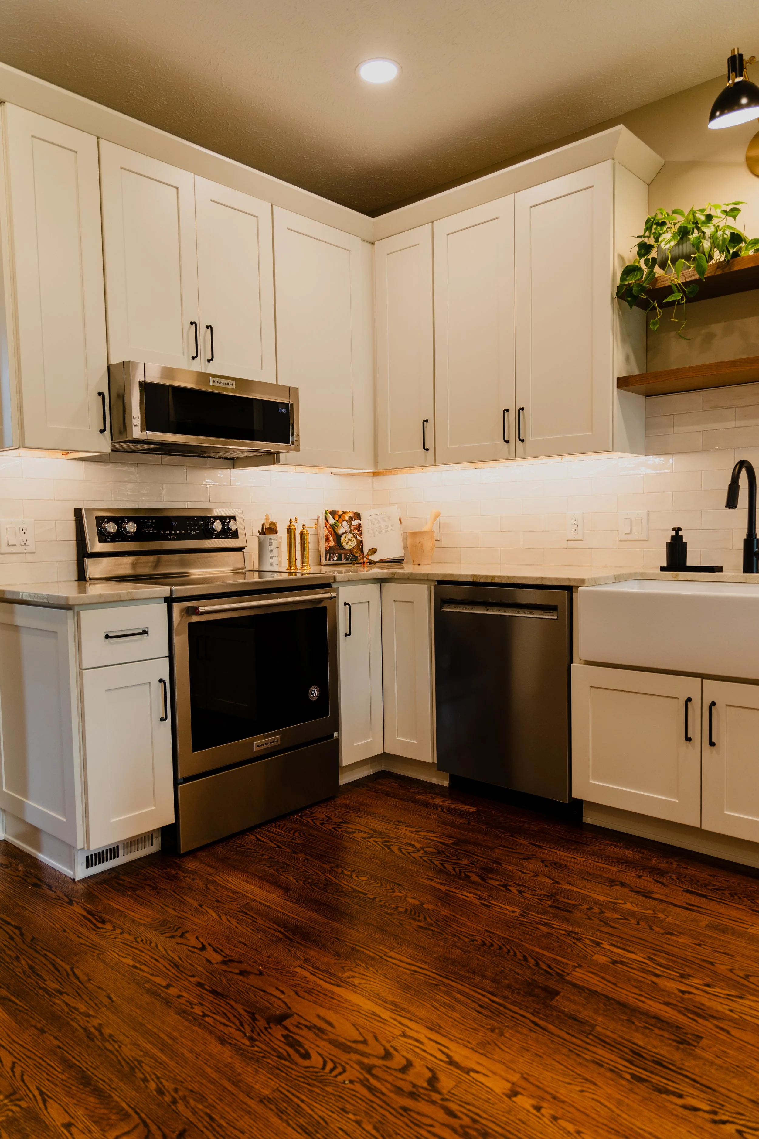 Kitchen with white cabinets, stainless steel appliances, and hardwood floors.