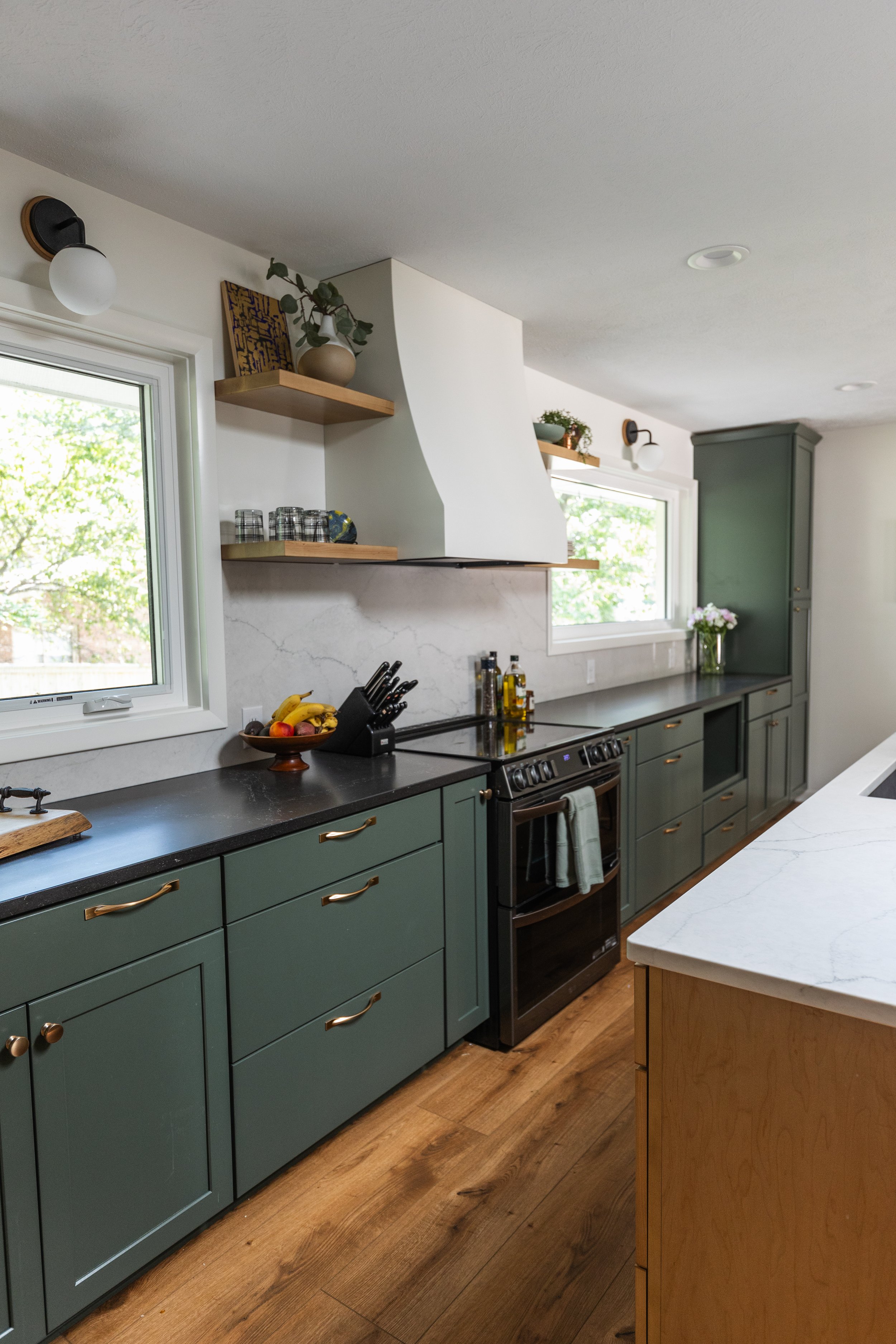 1962 Kitchen Remodel, dark green cabinets, white quartz island, wooden floors, brass hardware, wood cabinets, custom hood, floating shelves, dark countertops, open shelving