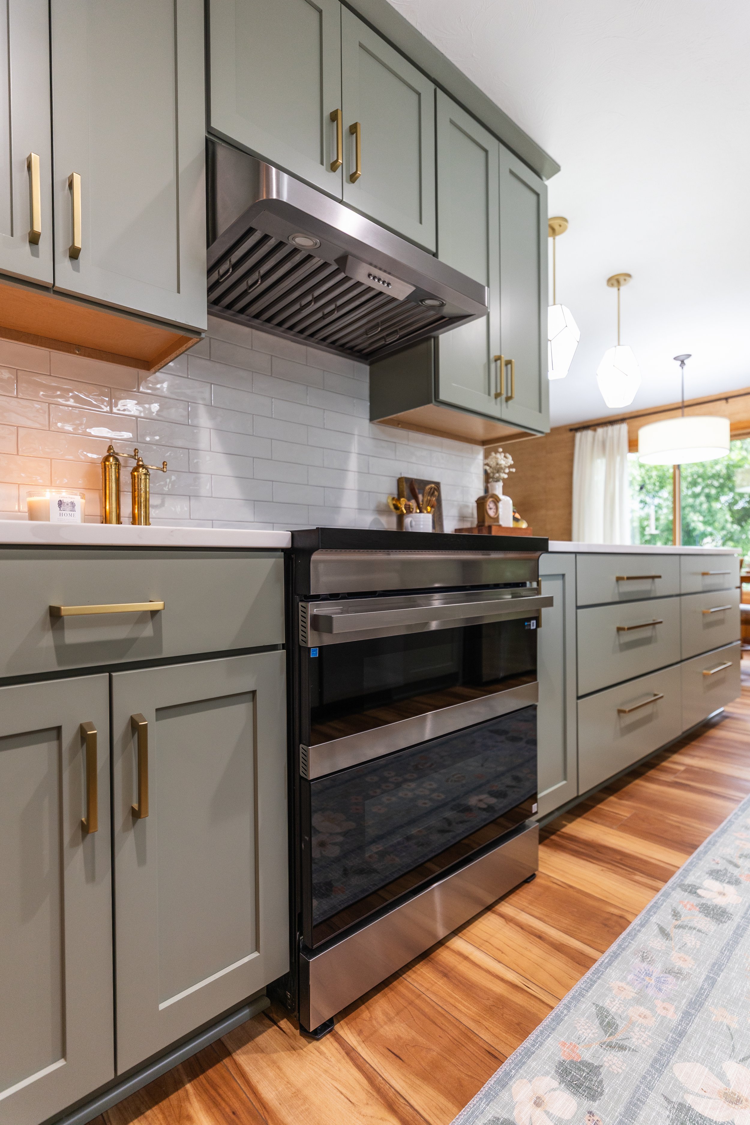 1958 Kitchen Remodel, mid century design, wood floors, stainless steel appliances, sage green cabinets, brushed gold hardware, white quartz countertop, modern light fixtures, Lincoln Nebraska, professional contractors, remodeling and renovations.