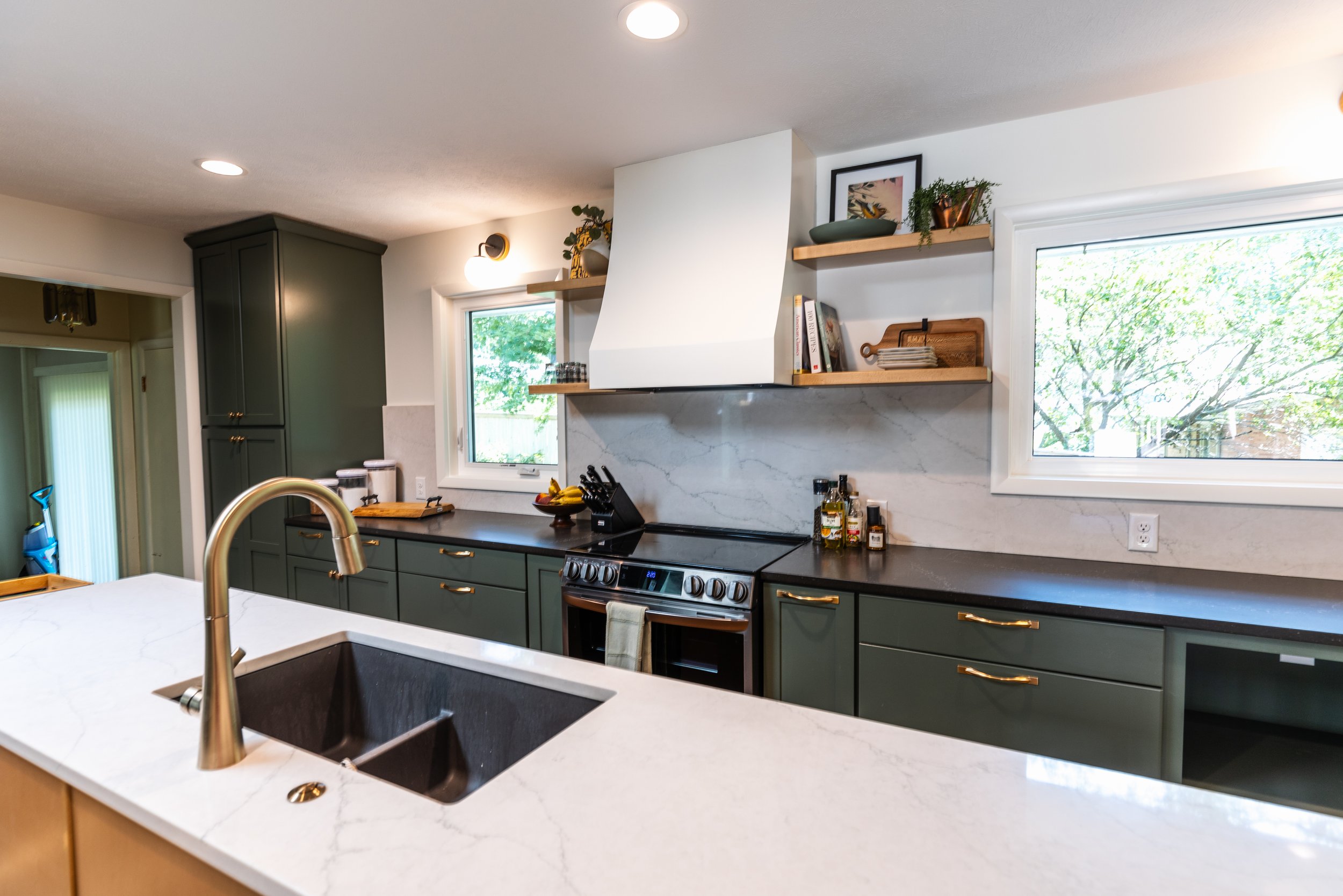 1962 Kitchen Remodel, dark green cabinets, white quartz island, wooden floors, brass hardware, wood cabinets, custom hood, floating shelves, dark countertops, open shelving