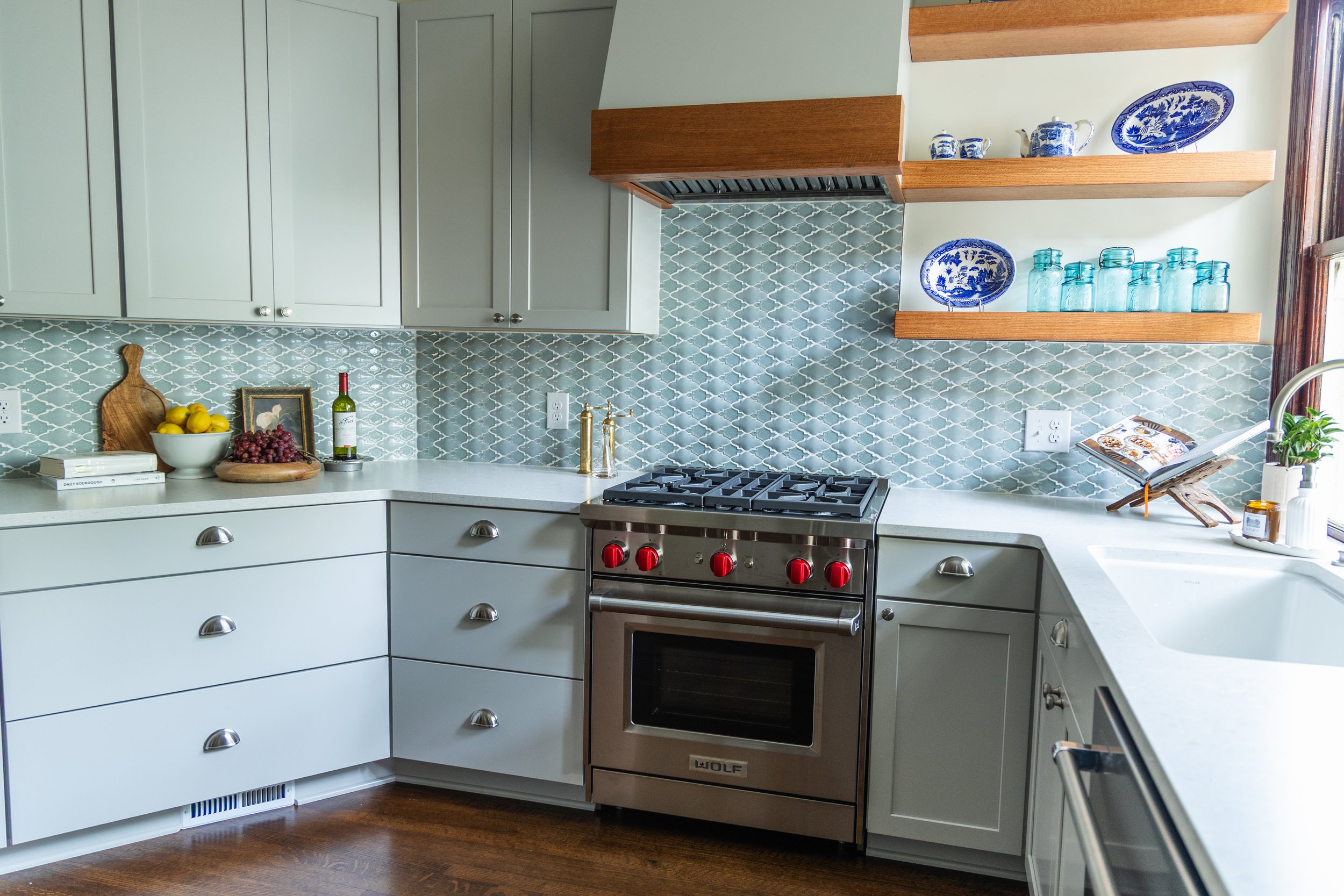 1900 Kitchen Remodel, wood floors, light blue tile backsplash, hardwood floors, open shelving, brushed nickel hardware, wolf oven, stainless steel appliances, custom hood, custom cabinetry, Omaha Nebraska, remodeling and renovations.