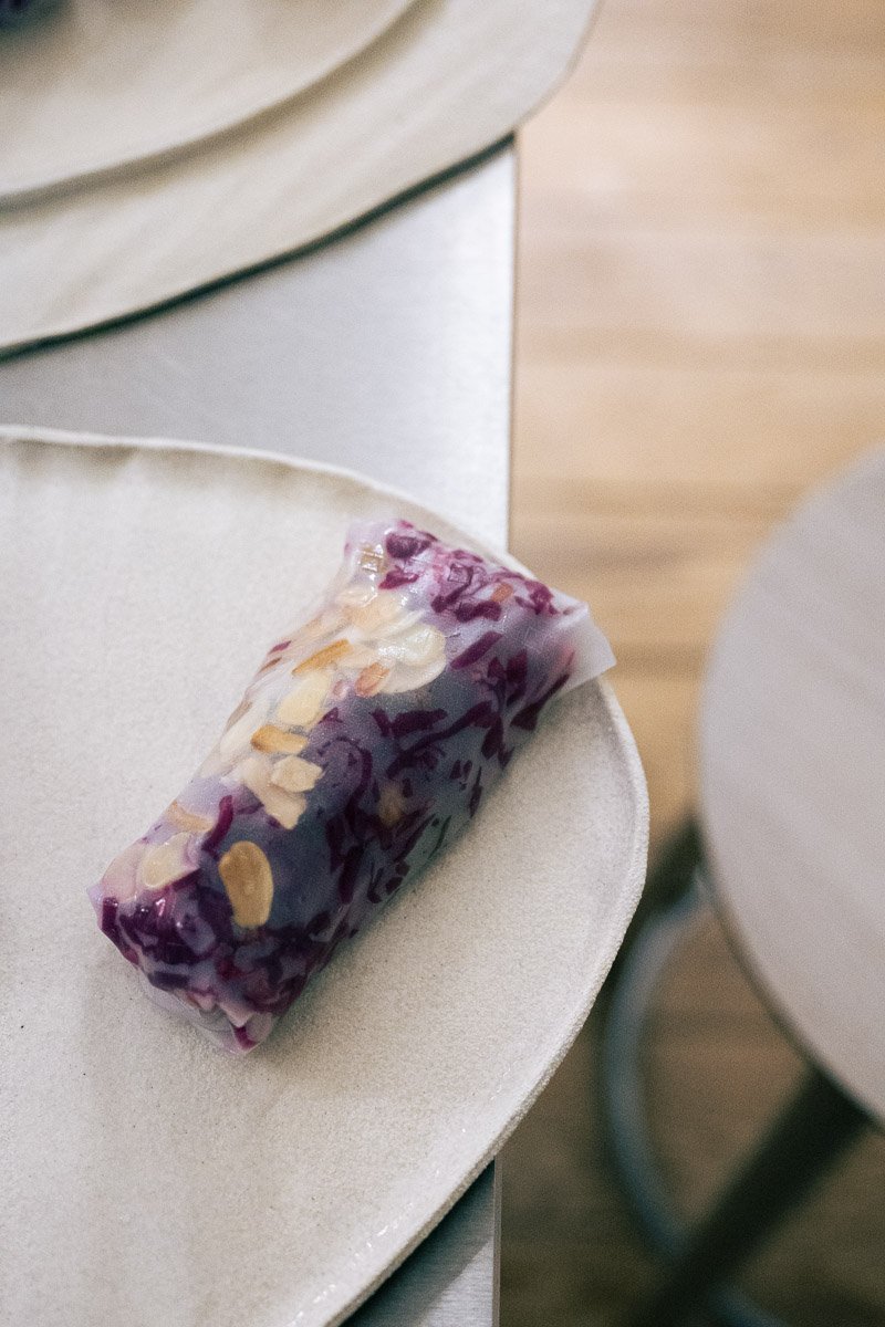 A small, cylindrical object wrapped in purple and clear plastic, placed on a white round table.