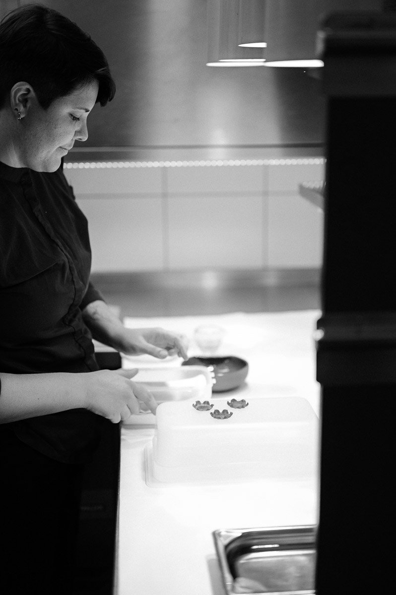 A woman preparing food or snacks at a kitchen counter in a modern, minimalistic kitchen.