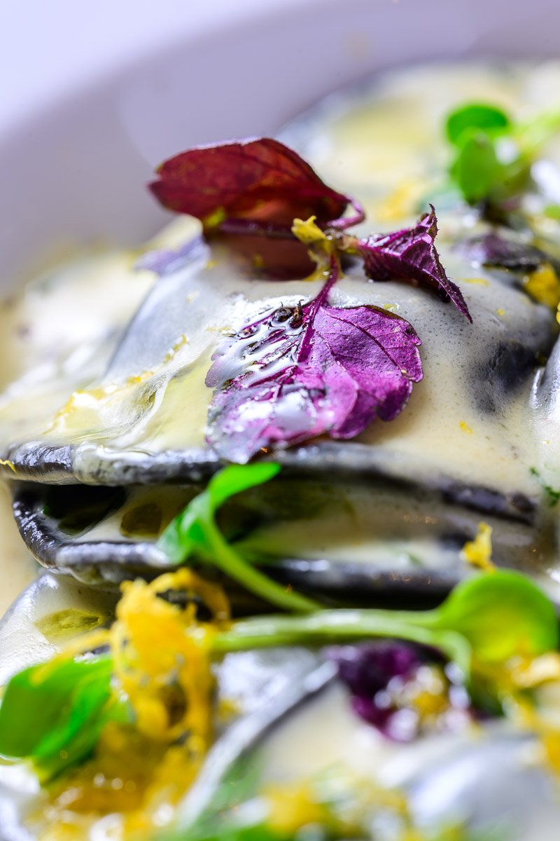 Close-up of mussels topped with colorful edible flowers and herbs.