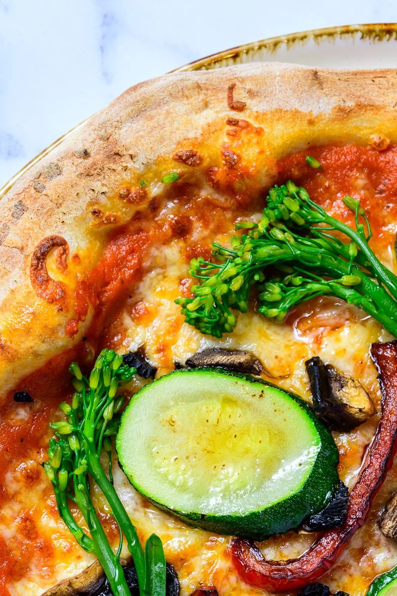 Close-up of a vegetable pizza with zucchini, broccoli, mushrooms, black olives, and cheese