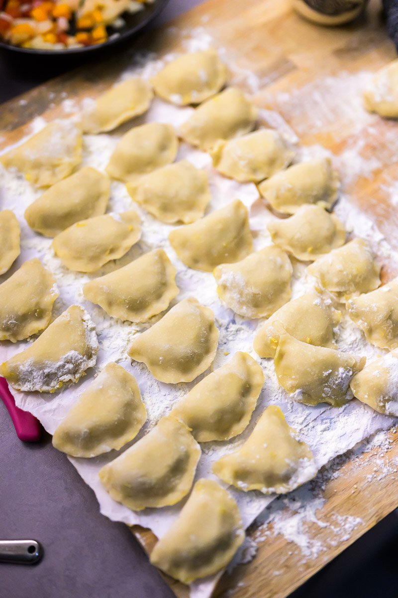 Dumplings on a floured wooden surface, ready to be cooked.