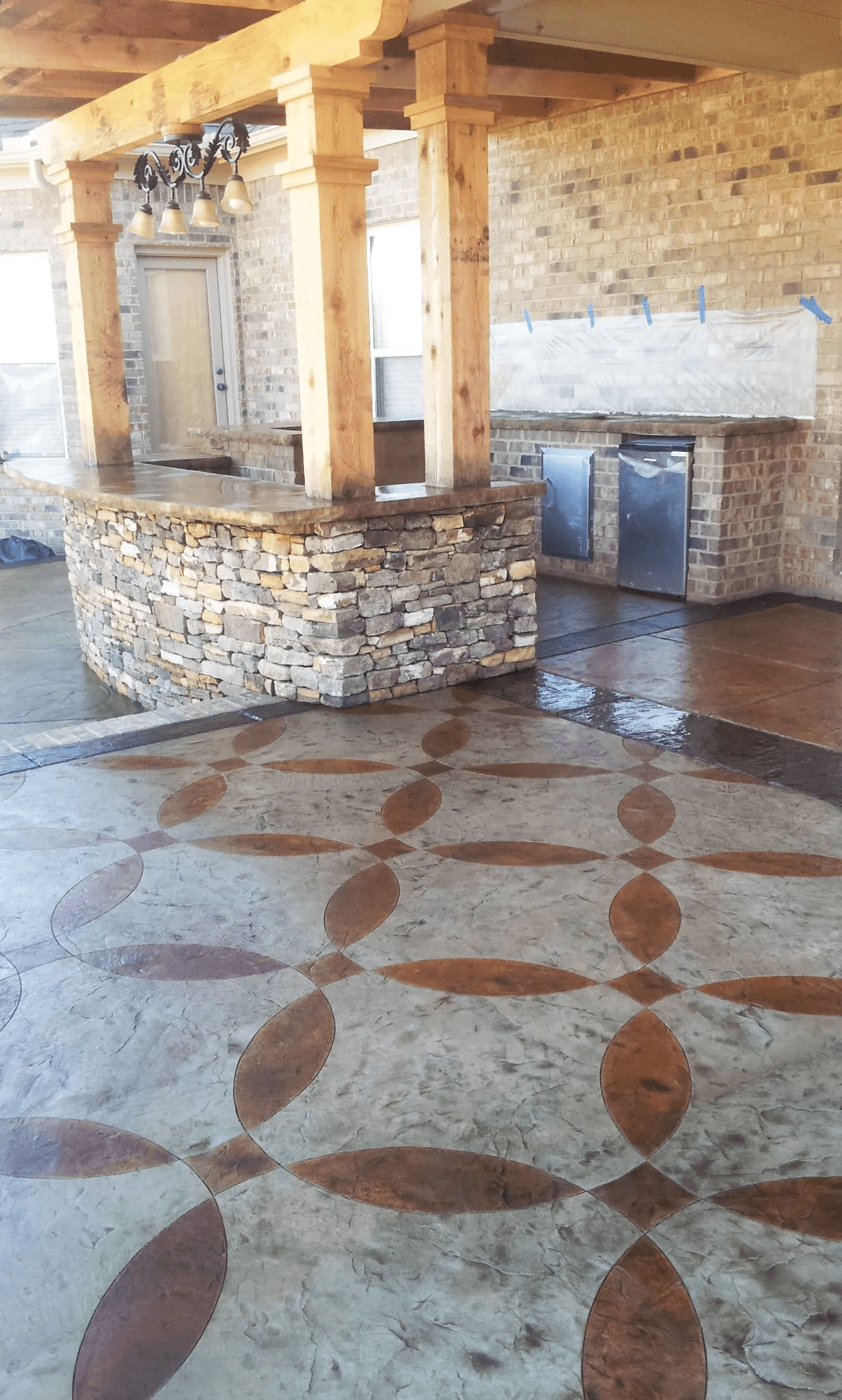 Outdoor patio area with a stone bar counter, brick walls, and decorative patterned concrete flooring.