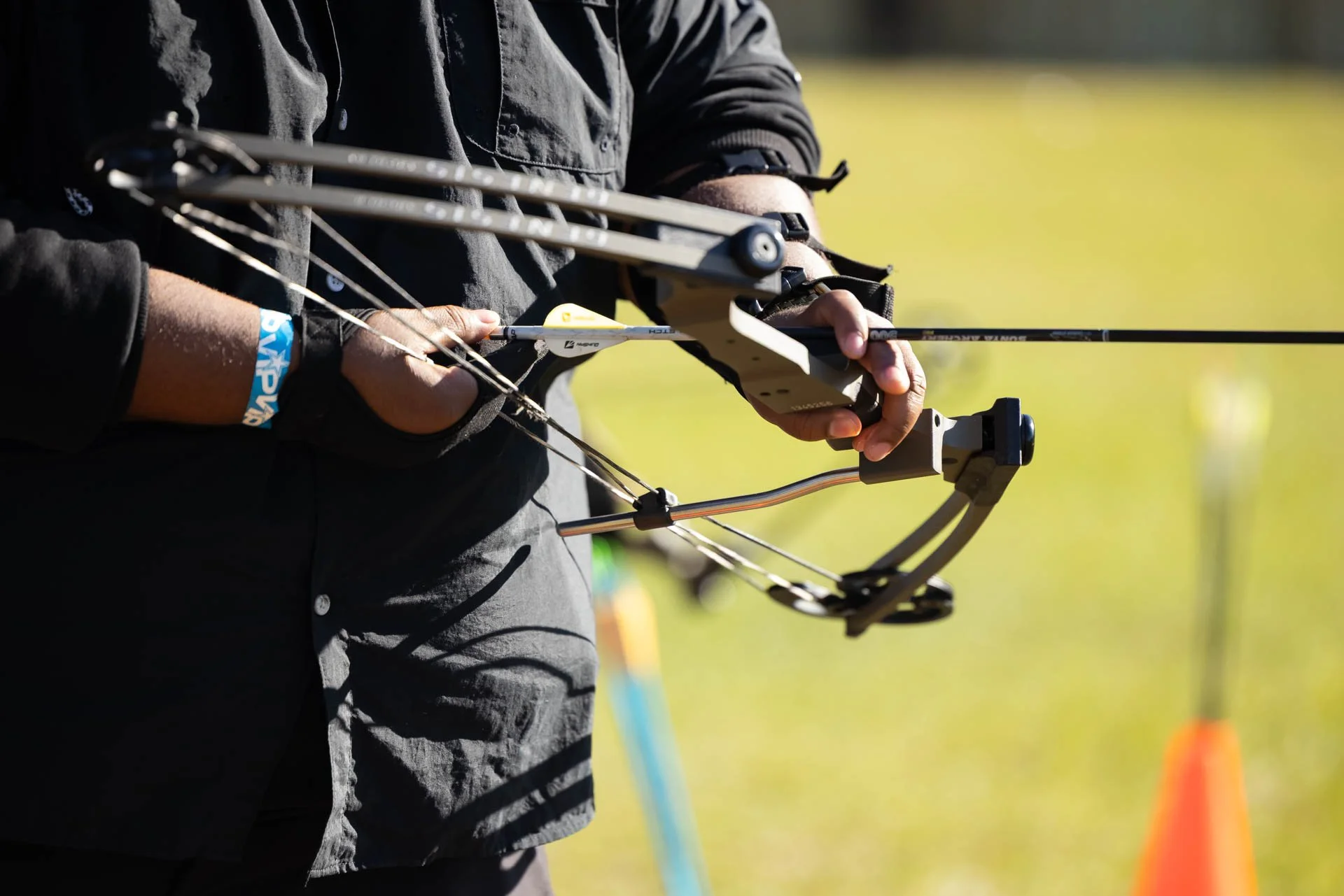 A person holding a bow and arrow in an outdoor setting, preparing to shoot.