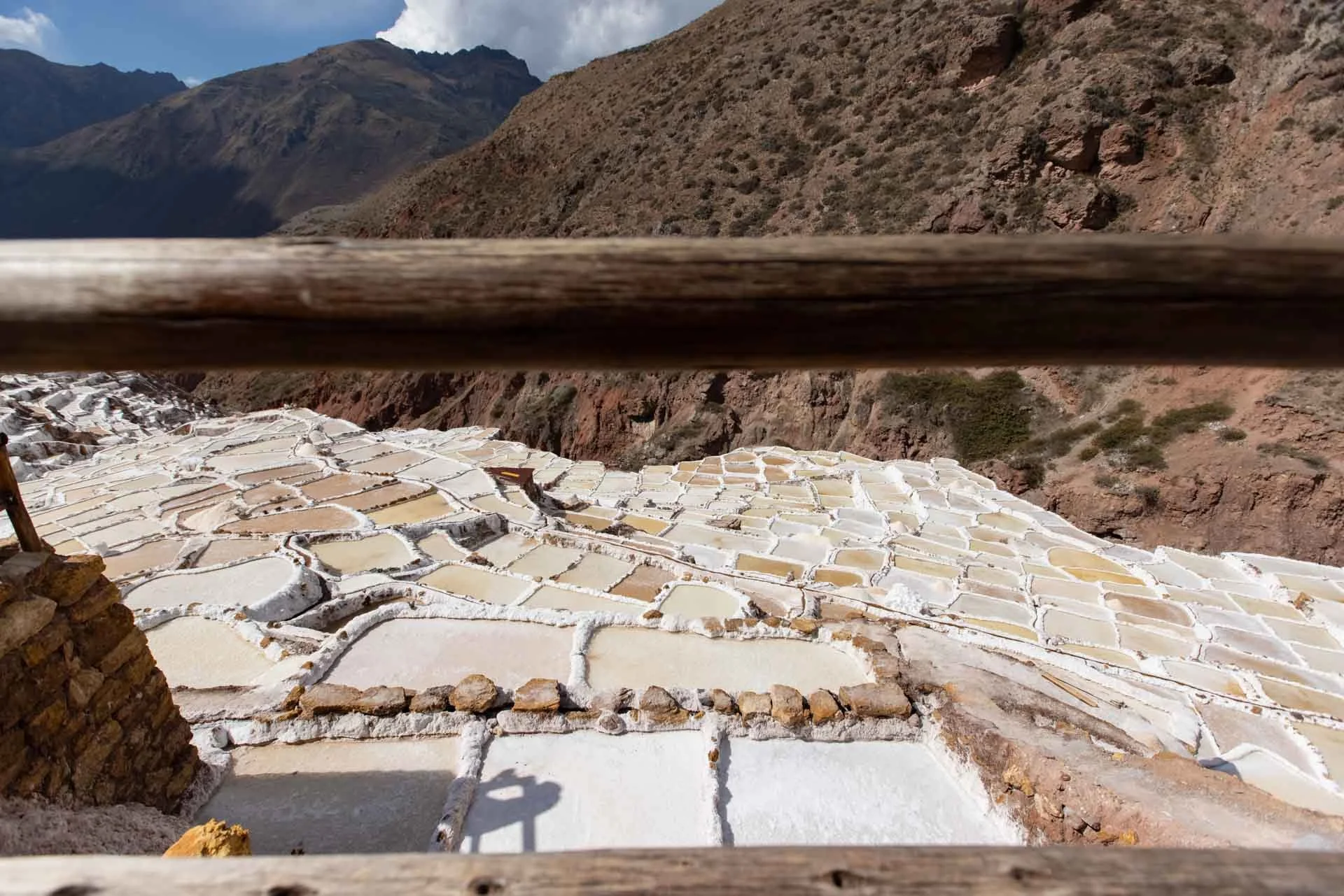 Salt terraces at Salinas de Maras in the Peruvian Andes, with reddish-brown mountains in the background.