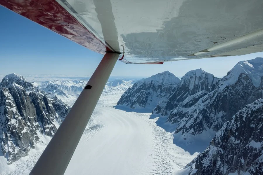 Aerial view of snow-covered mountains and a glacier captured from an airplane.