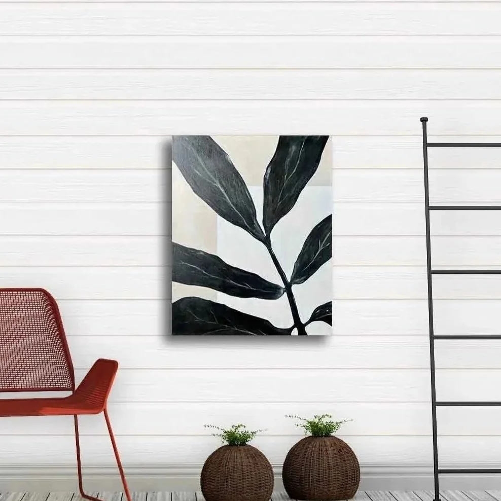 Interior with a white paneled wall, a black and white leaf art print, a red modern chair, and two wicker planters with small green plants.