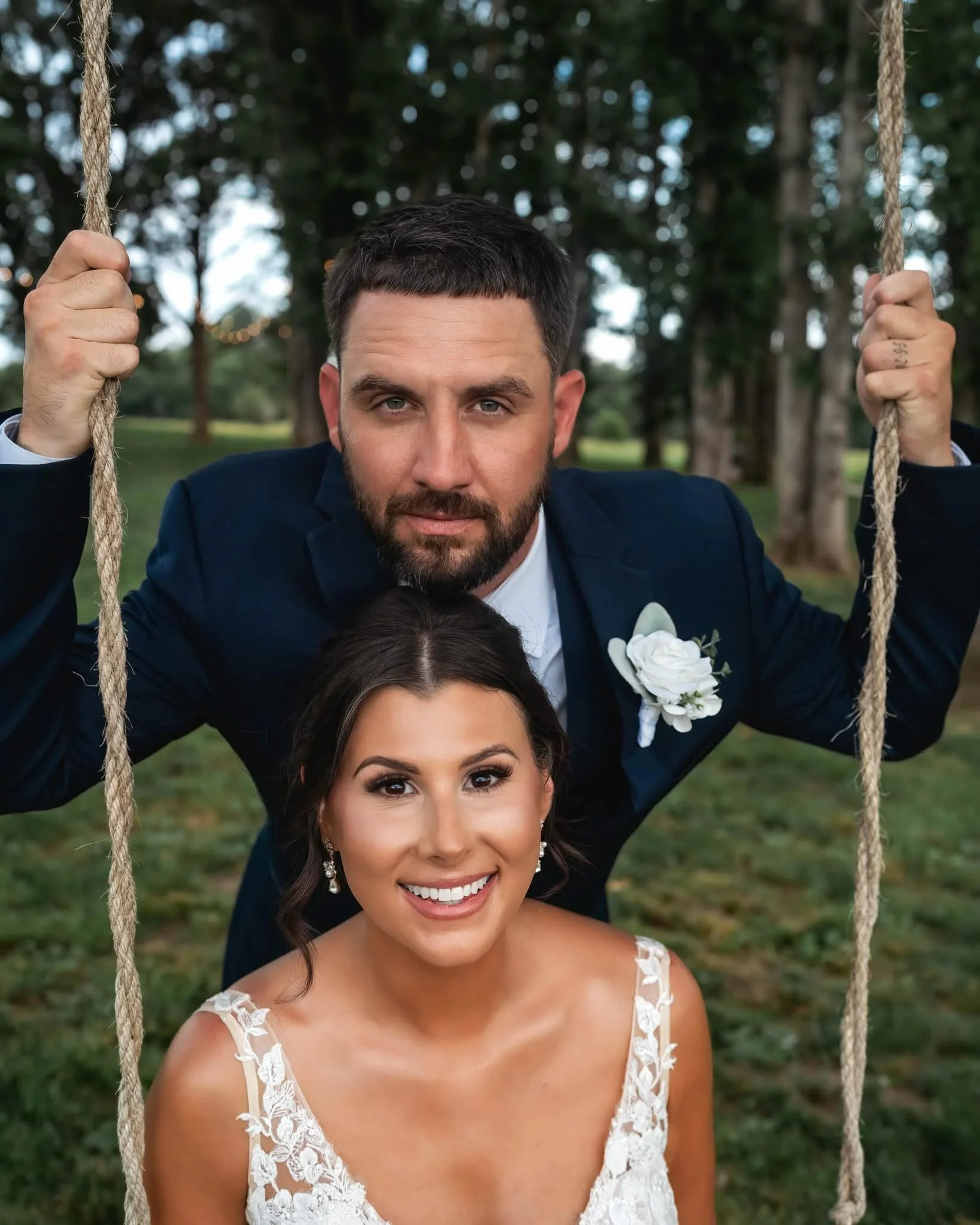 St. Louis Wedding Venue, Berkshire Ridge, offers a magical area under a big oak tree with a rope swing and lanterns.  A bride is on the swing with the groom holding the ropes above her and leaning into the bride with a serious face