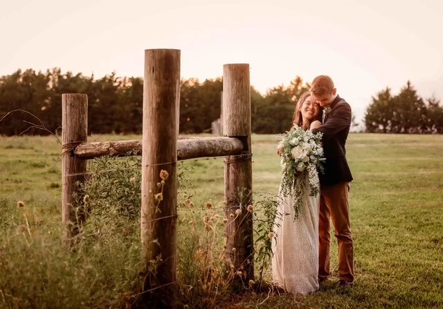 A wedding photo at Berkshire Ridge Wedding Venue just south of St. Louis.  It is a couple hugging - the groom is behind the bride with his arms wrapped around her.  The brides eyes are closed.  Her beautiful bouquet is white roses with green.